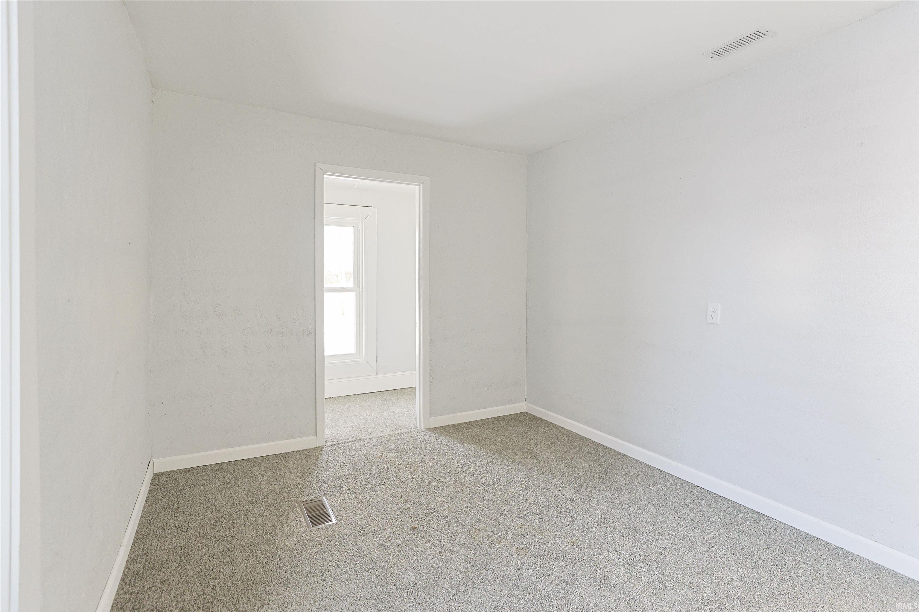 Unfurnished room featuring baseboards and light carpet
