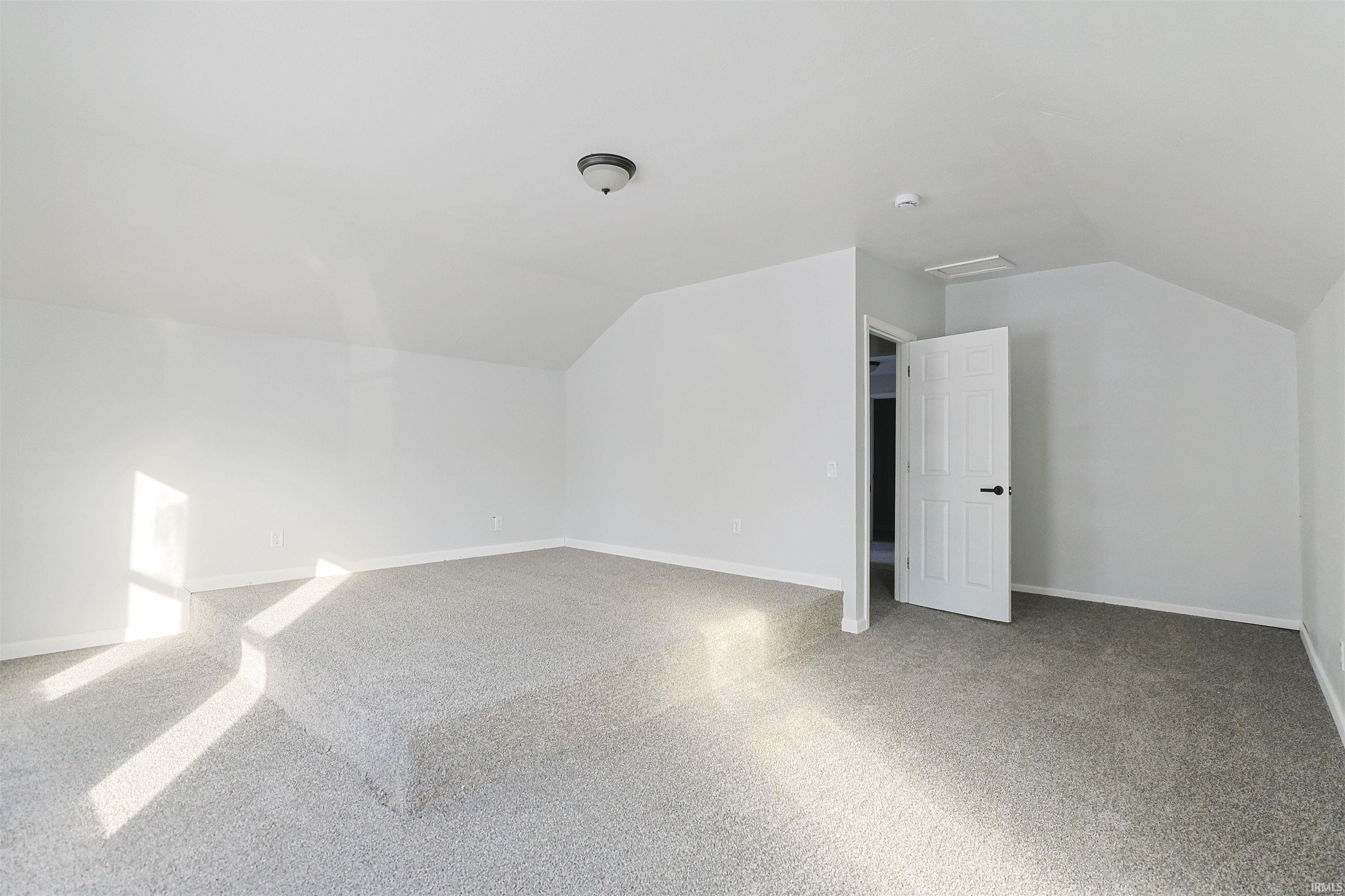 Additional living space featuring lofted ceiling and light carpet