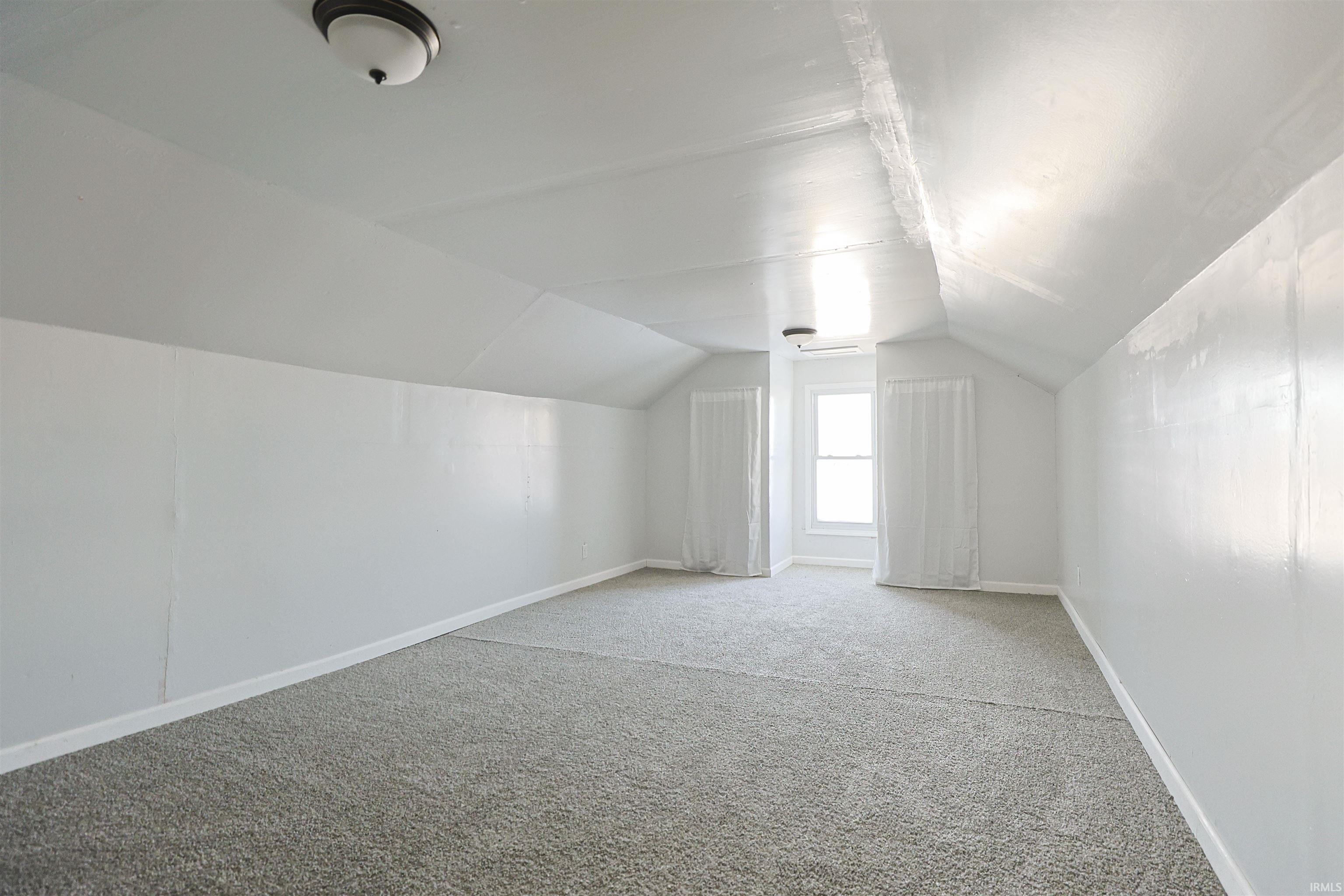 Additional living space featuring lofted ceiling and carpet floors