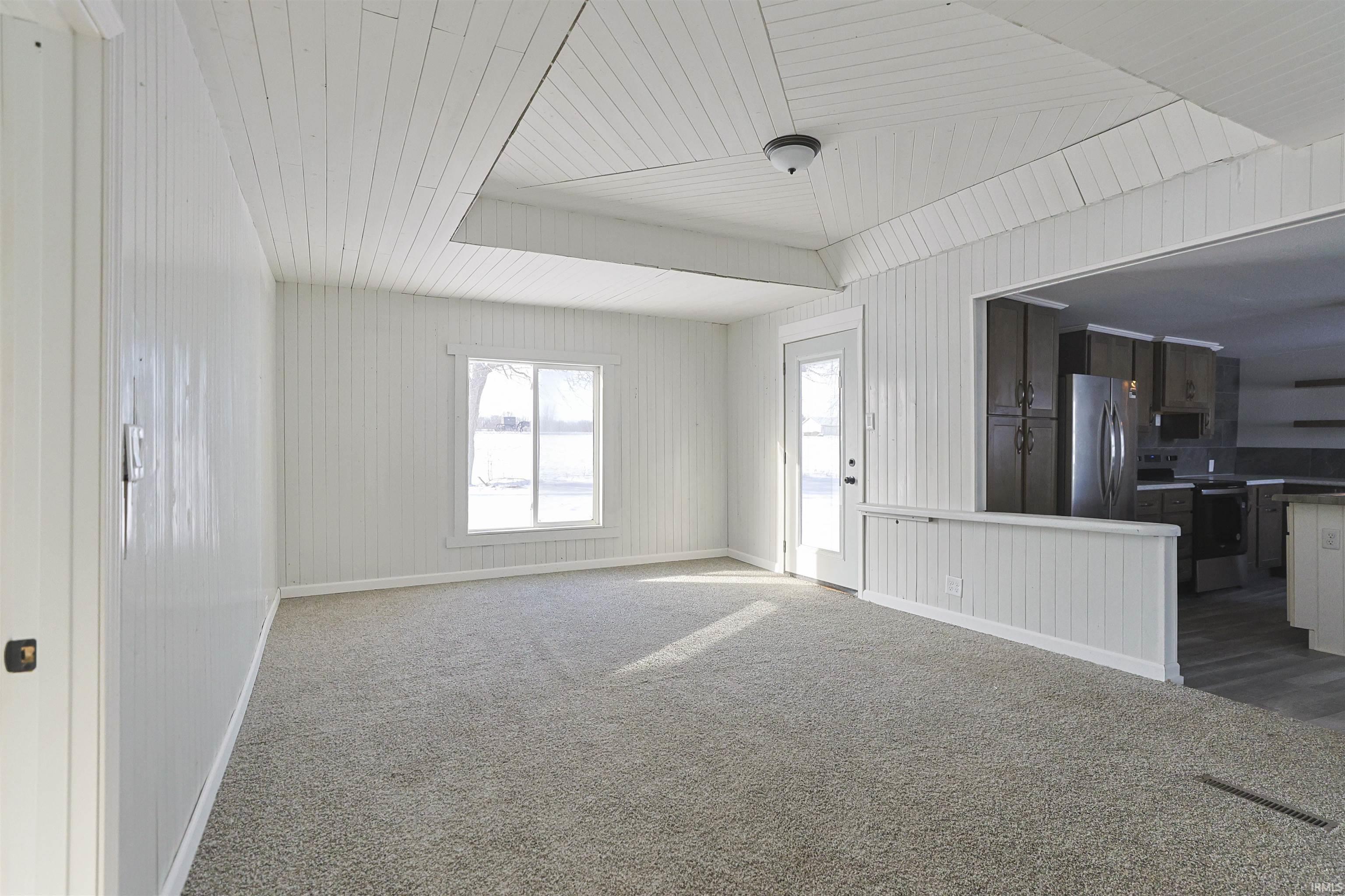 Unfurnished living room with dark colored carpet and wood ceiling