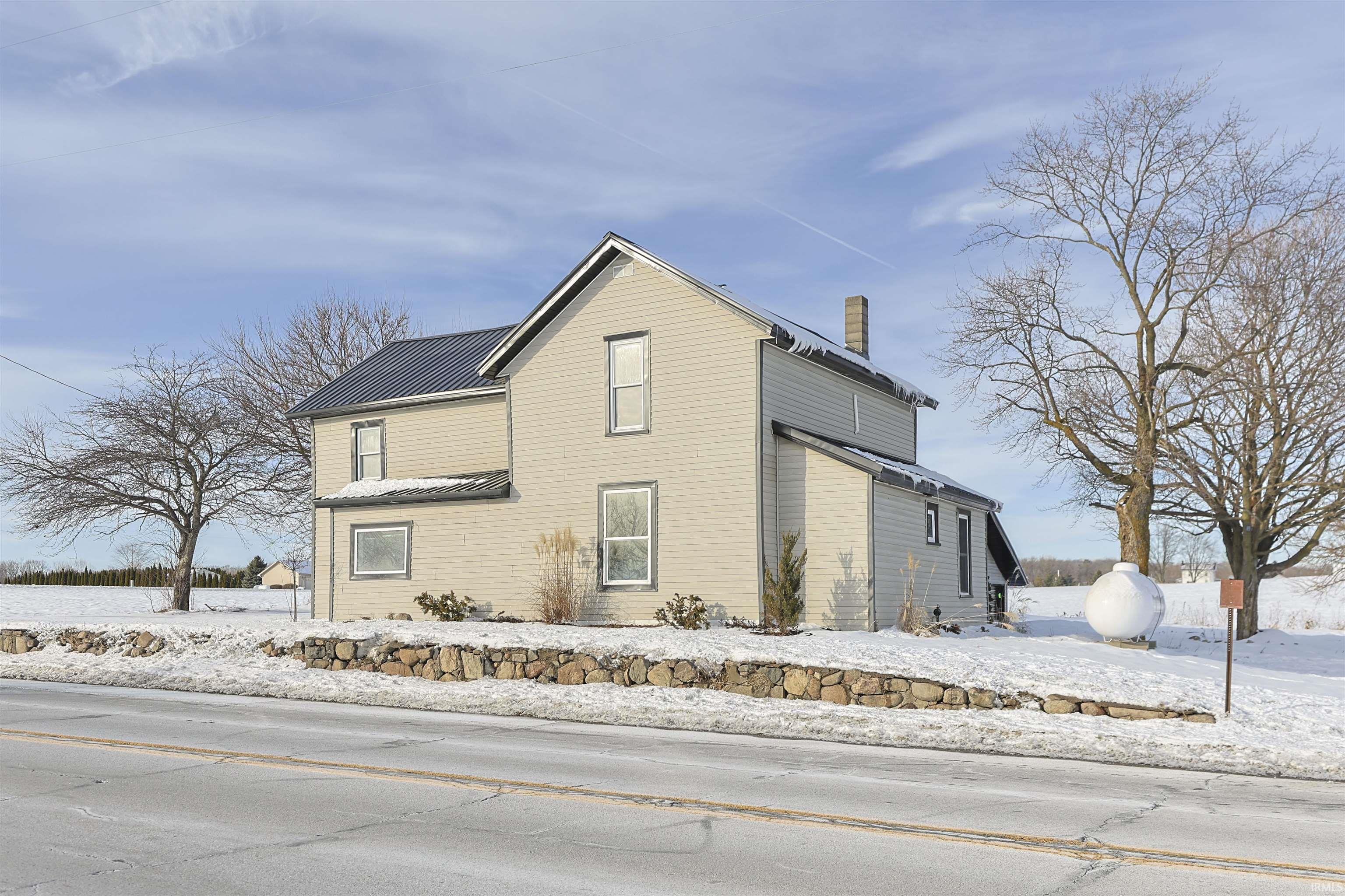 View of snow covered exterior with a chimney, a metal roof, and a standing seam roof