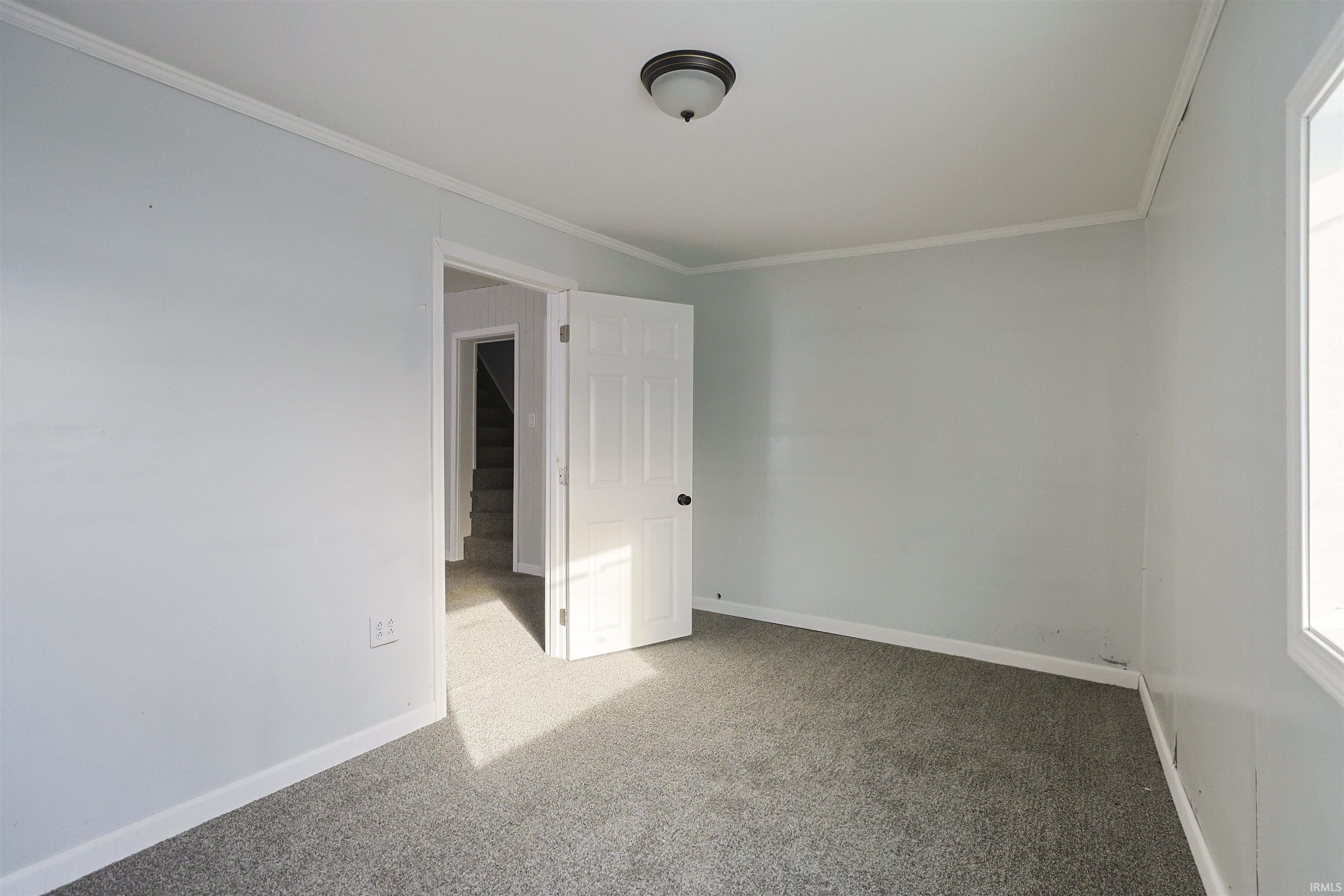 Empty room with ornamental molding and carpet floors