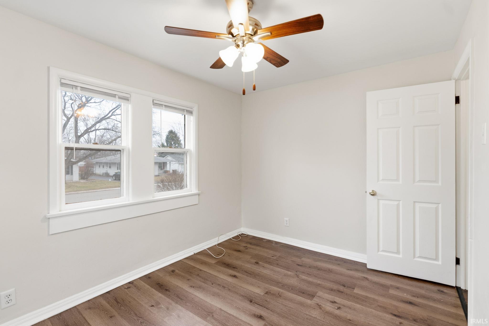 Empty room with wood finished floors and a ceiling fan