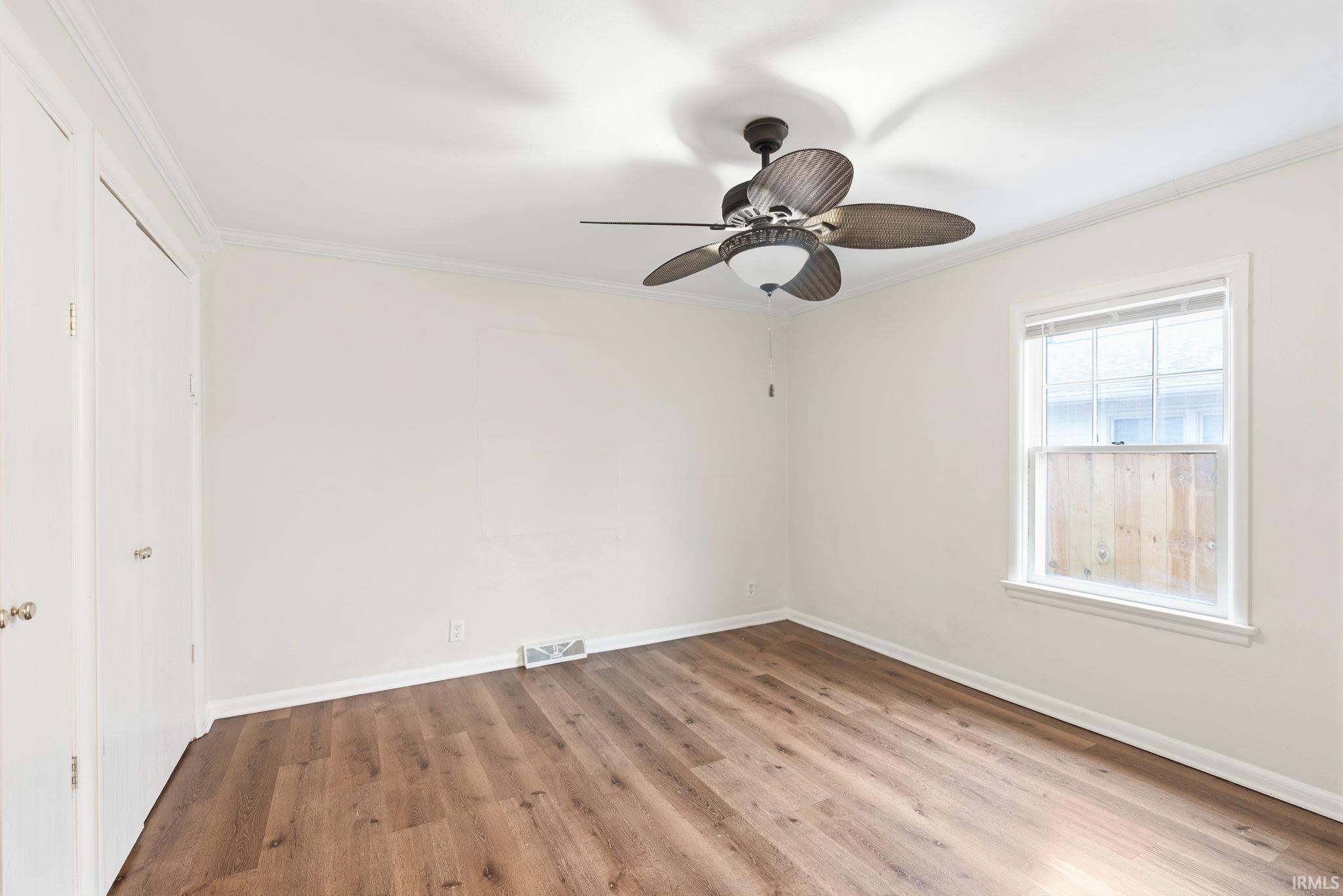 Unfurnished bedroom with crown molding, light wood-style floors, and ceiling fan