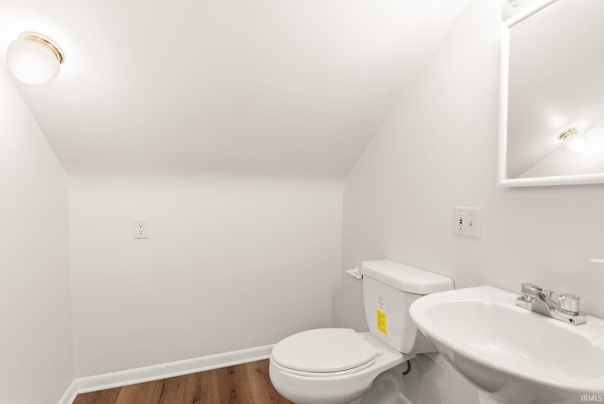 Half bath with wood finished floors and lofted ceiling