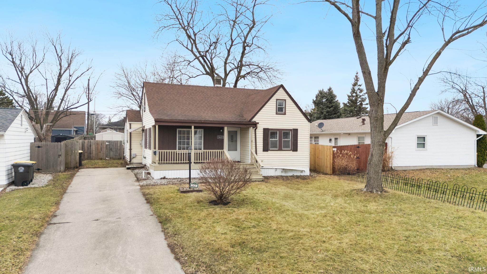 View of front facade featuring covered porch, roof with shingles, and concrete driveway