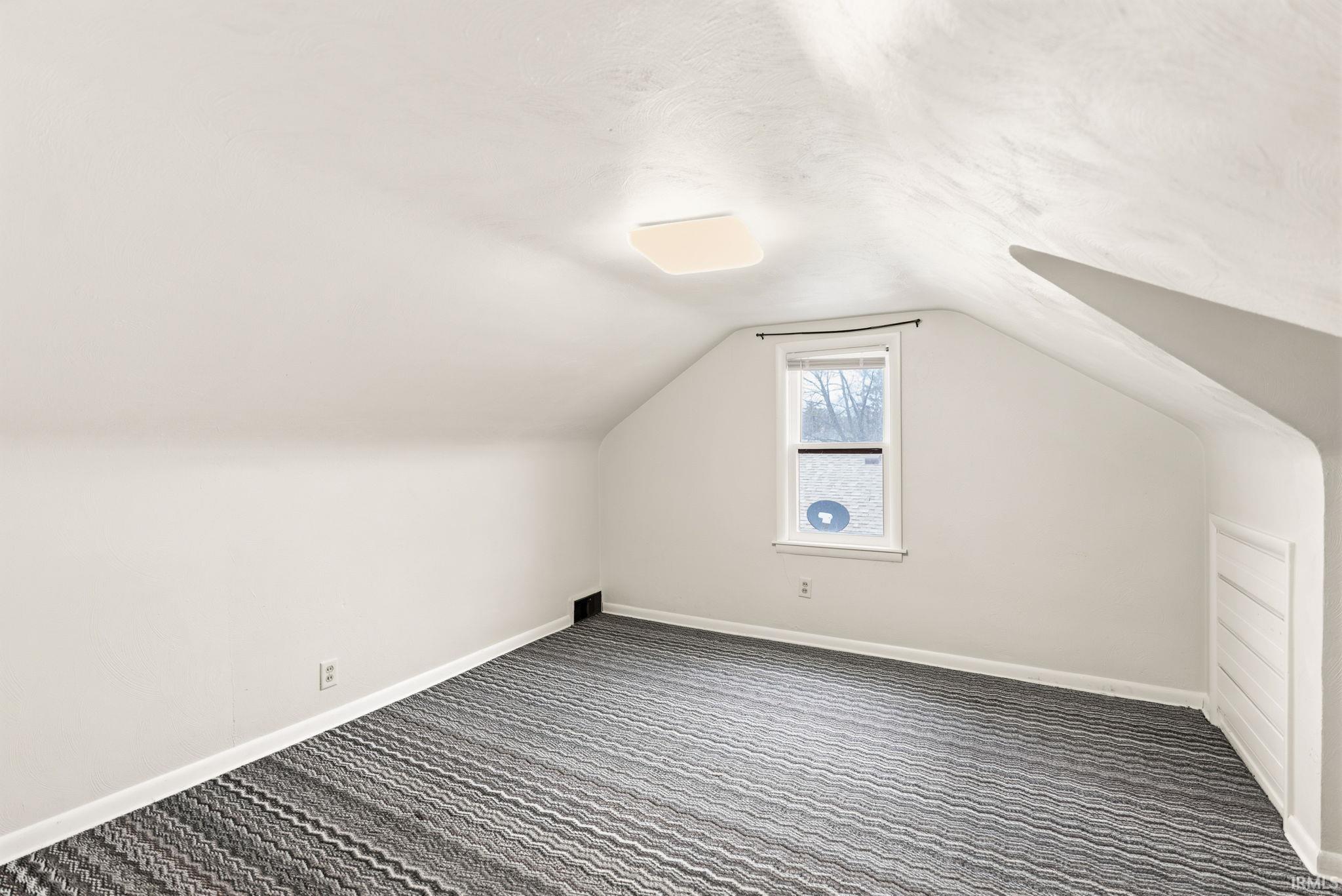 Additional living space featuring baseboards and dark carpet
