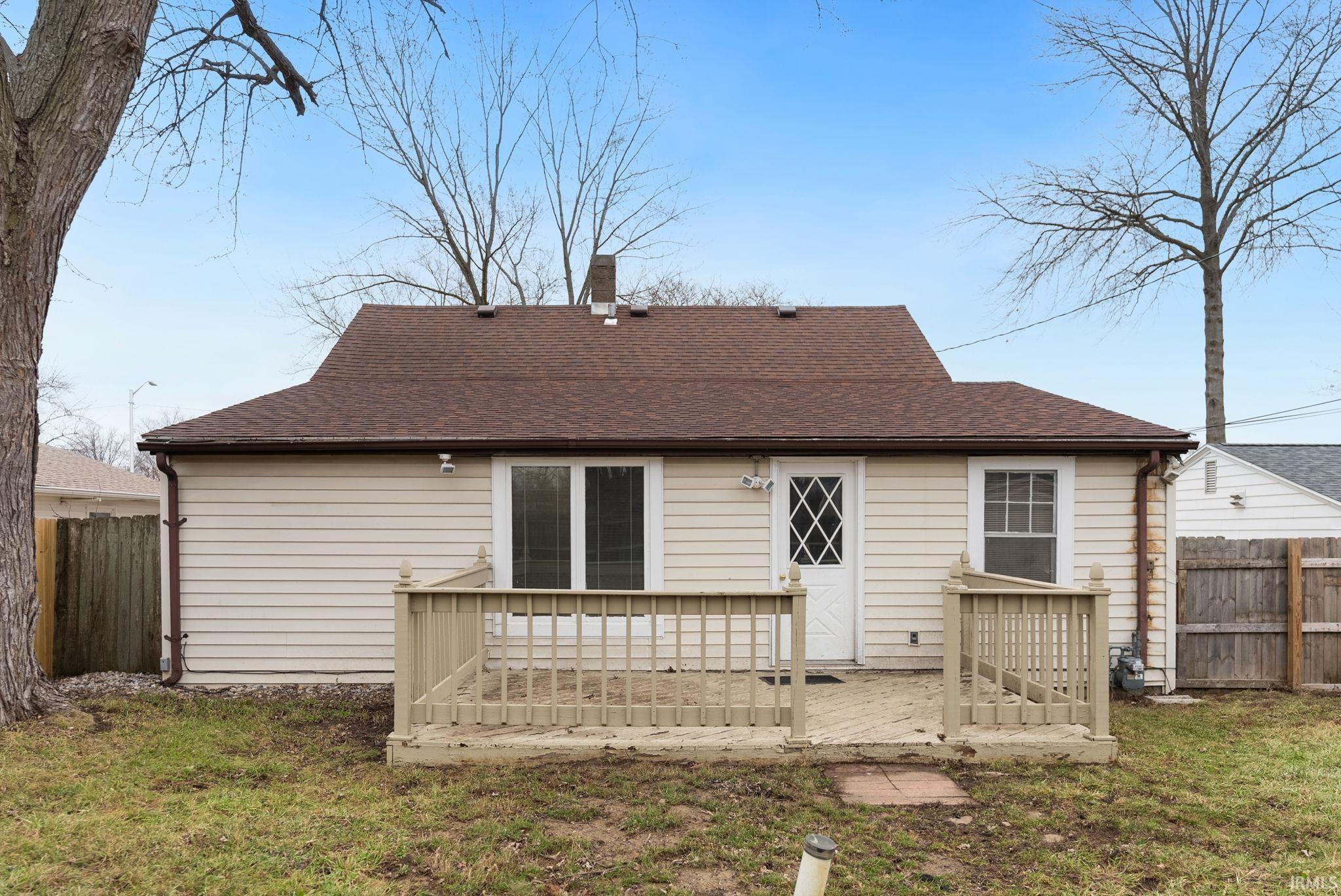 Rear view of property featuring a wooden deck, a chimney, and roof with shingles