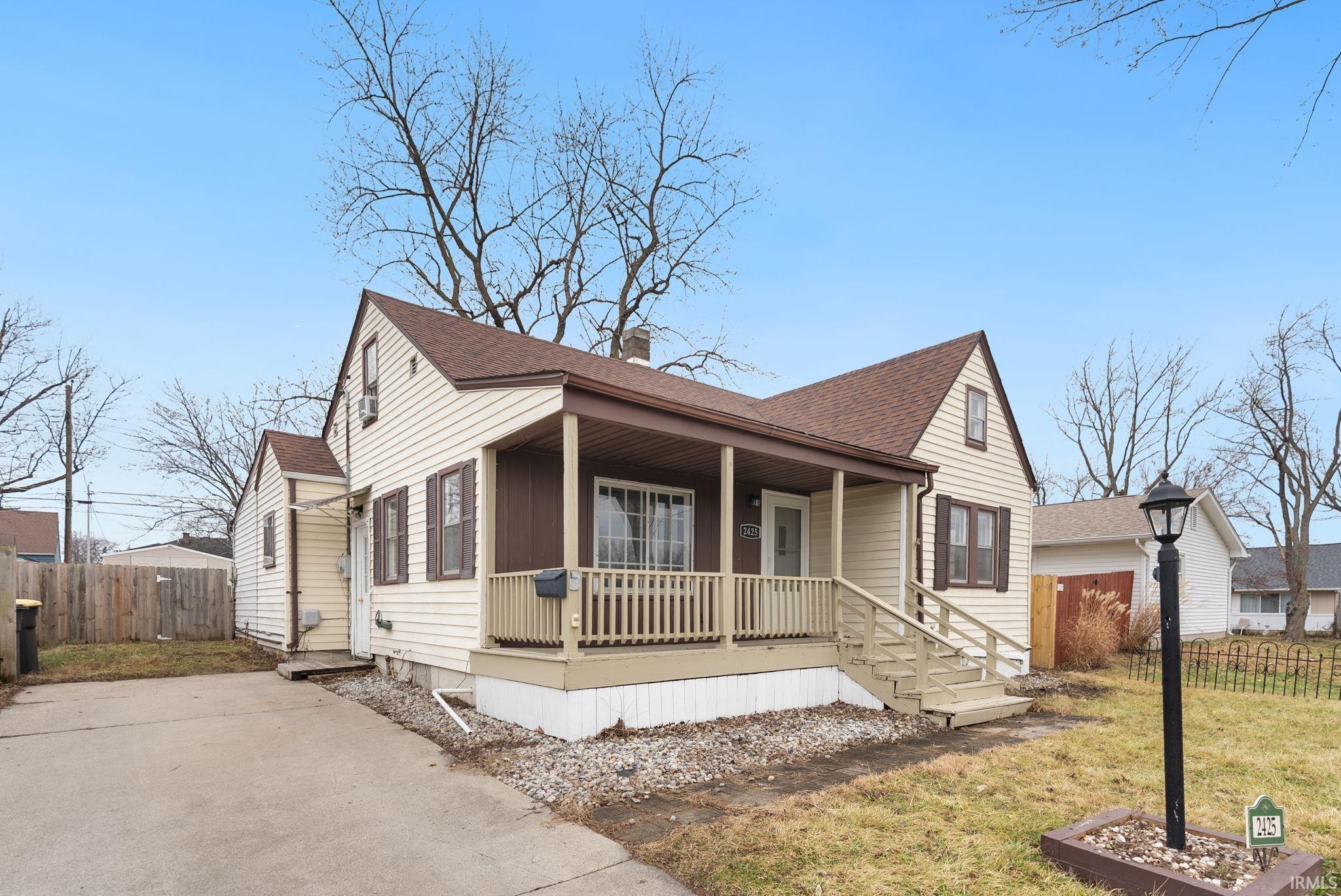 View of front of property with a porch, roof with shingles, and a chimney