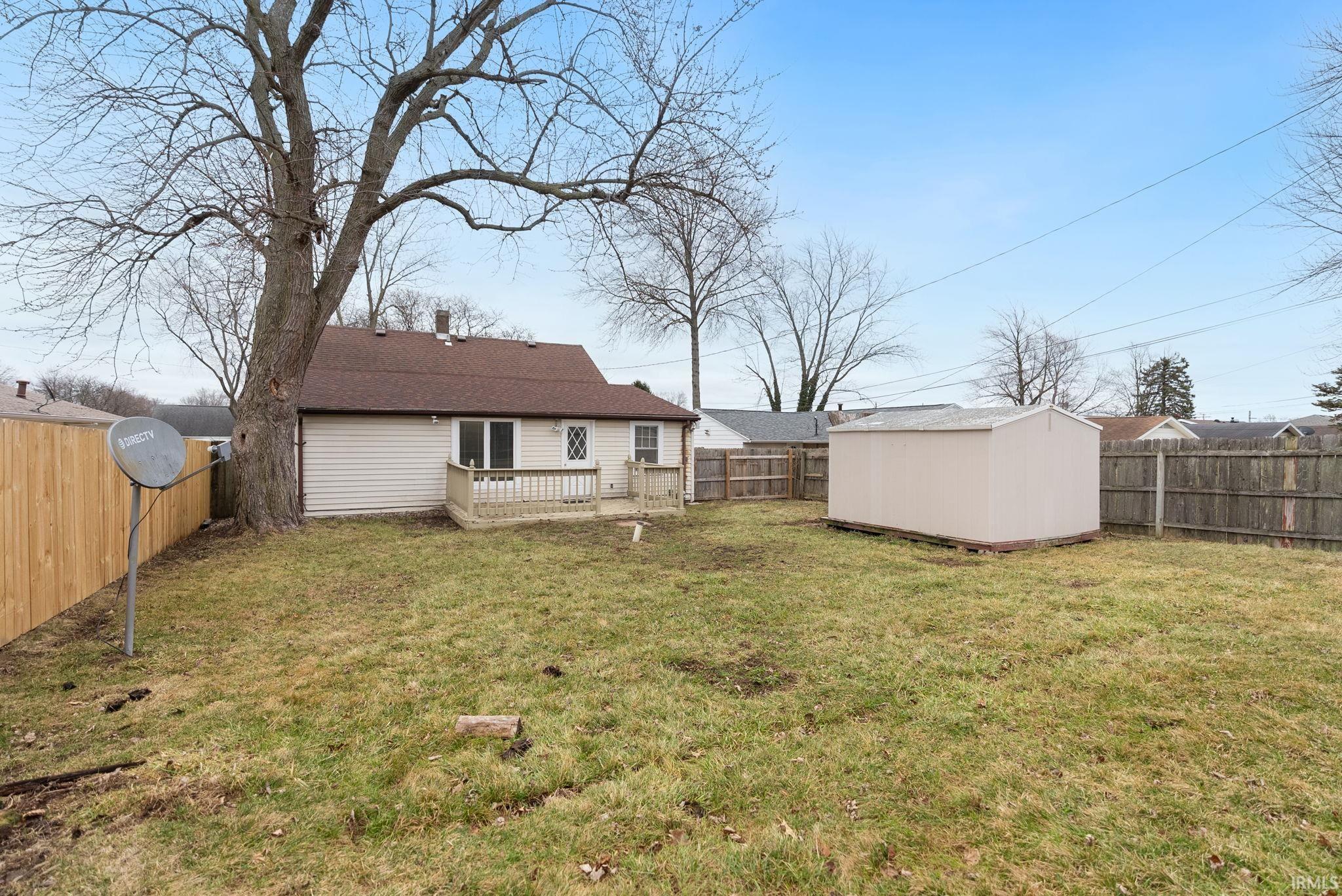 Rear view of house with a storage unit, a deck, and a fenced backyard