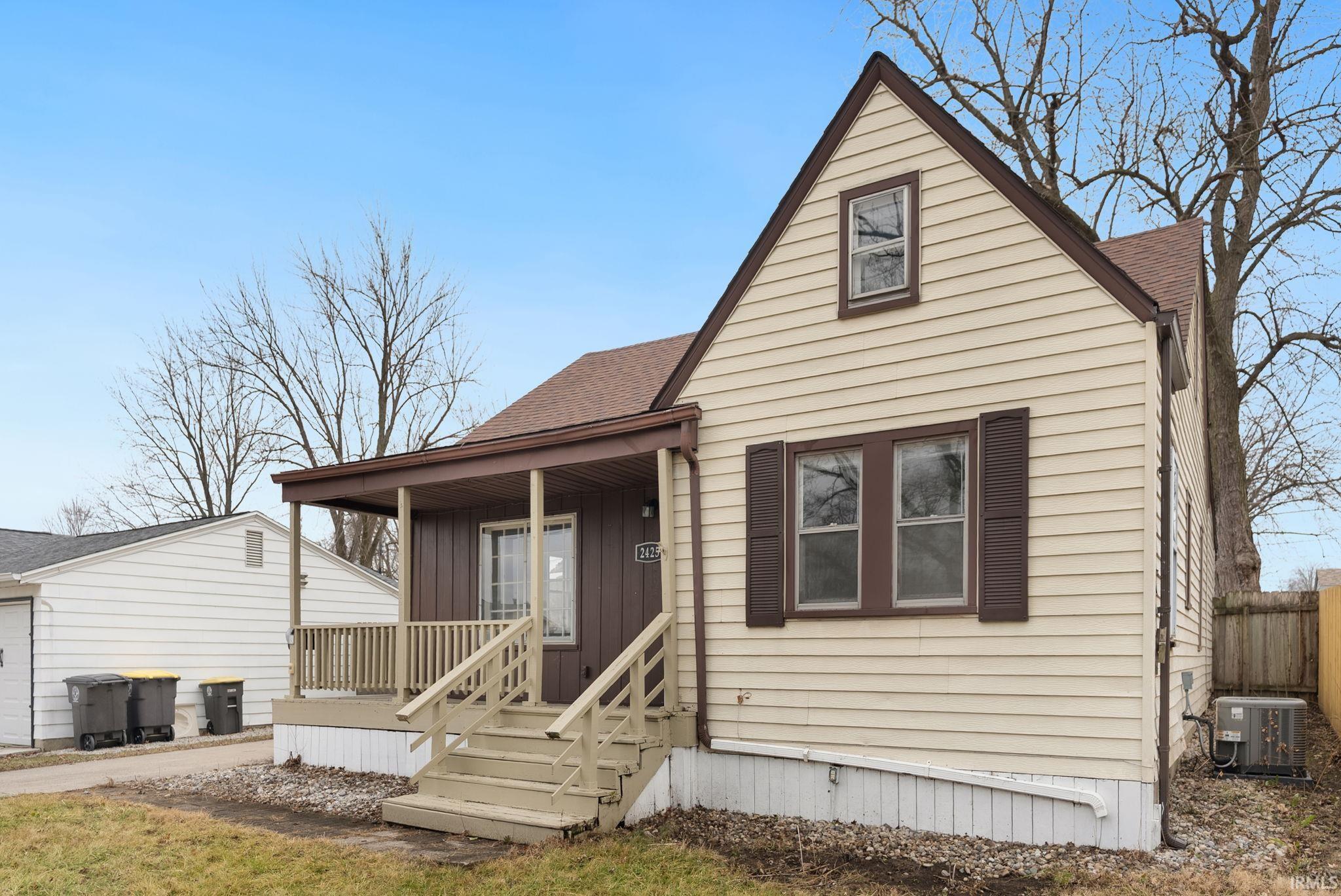 View of front facade with covered porch, roof with shingles, and board and batten siding