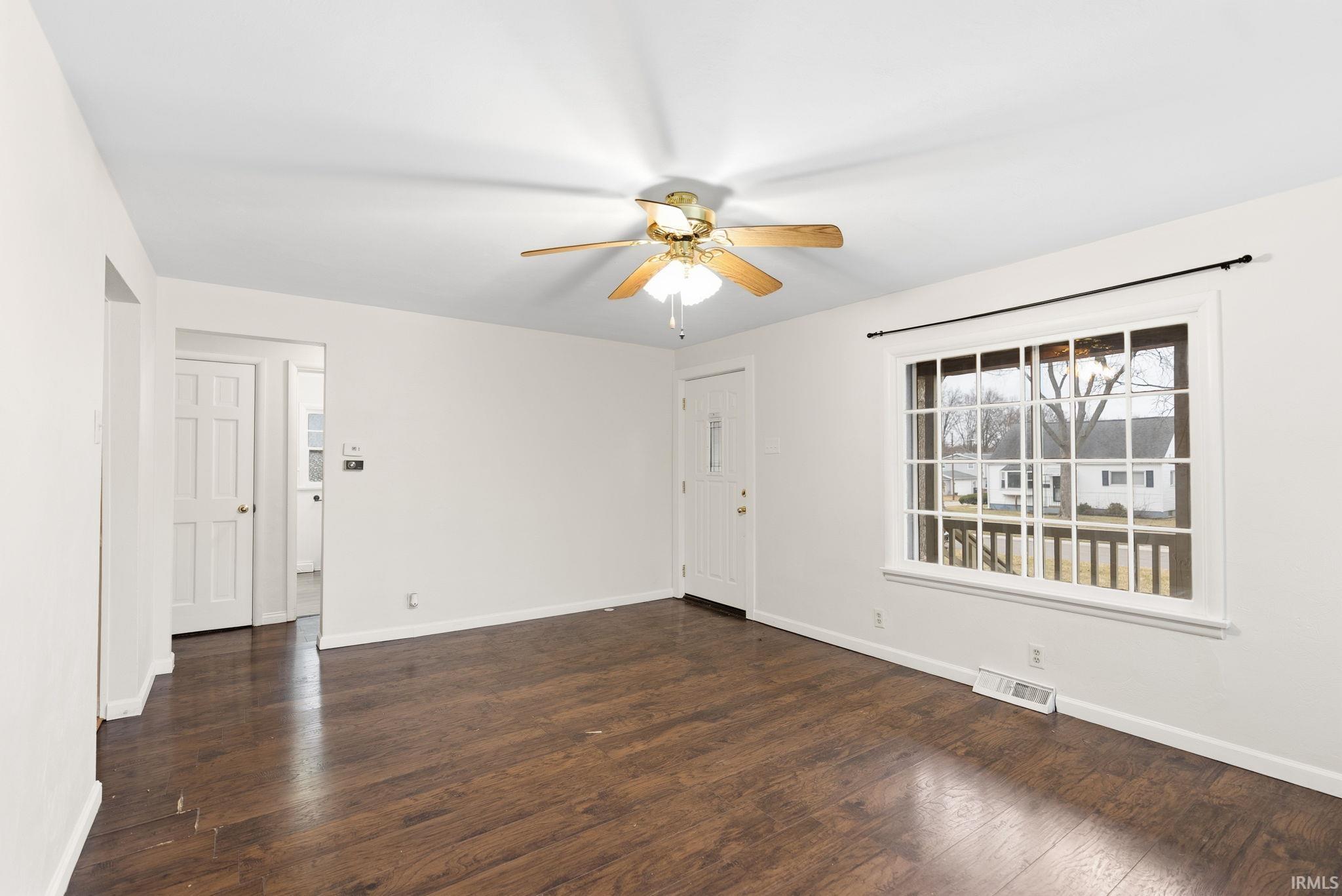 Empty room with dark wood-style floors and a ceiling fan