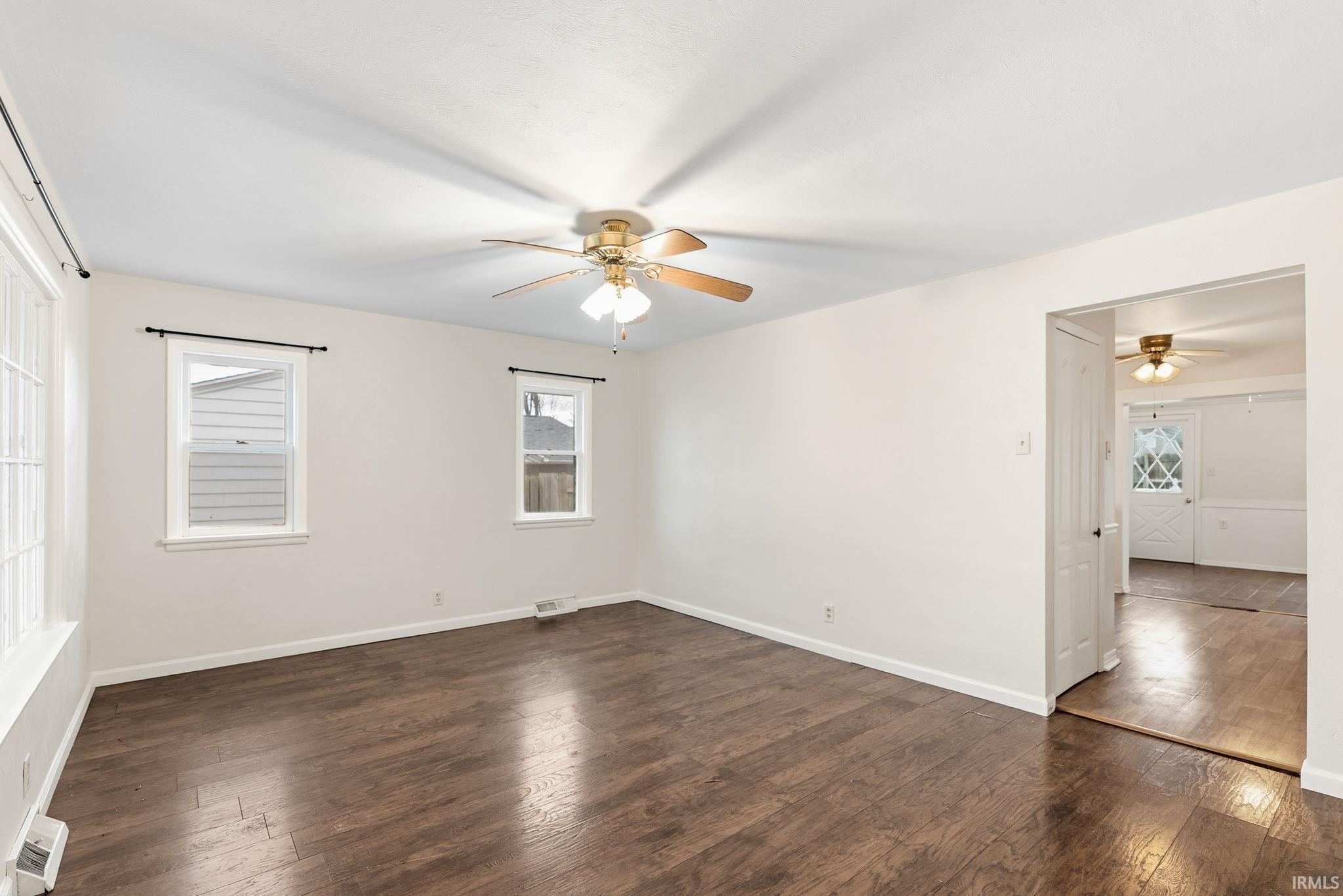 Empty room featuring dark wood-type flooring and a ceiling fan