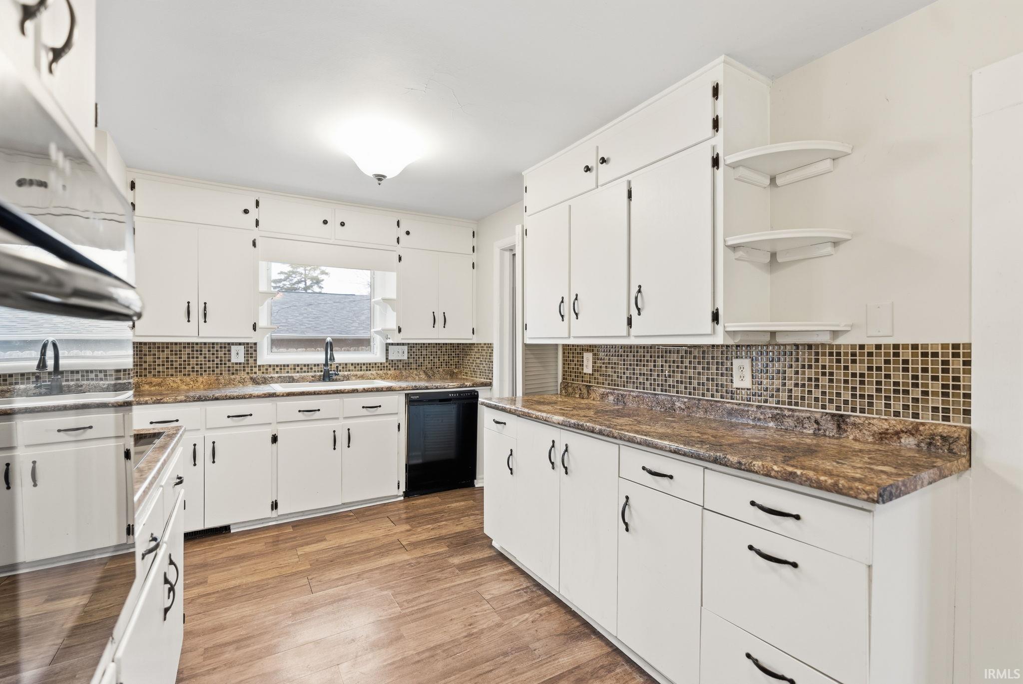 Kitchen with open shelves, light wood-type flooring, white cabinetry, and black dishwasher