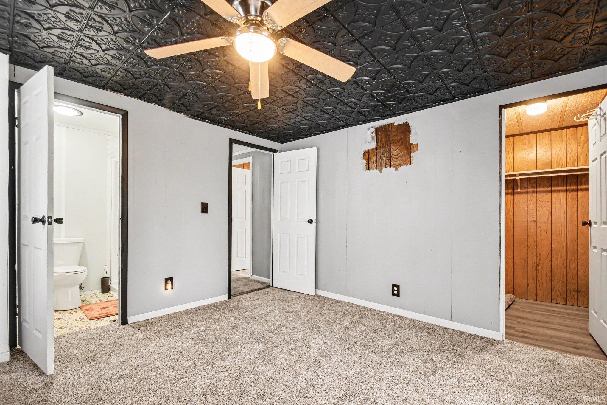 Unfurnished bedroom with ensuite bath, an ornate ceiling, carpet floors, a ceiling fan, and a closet