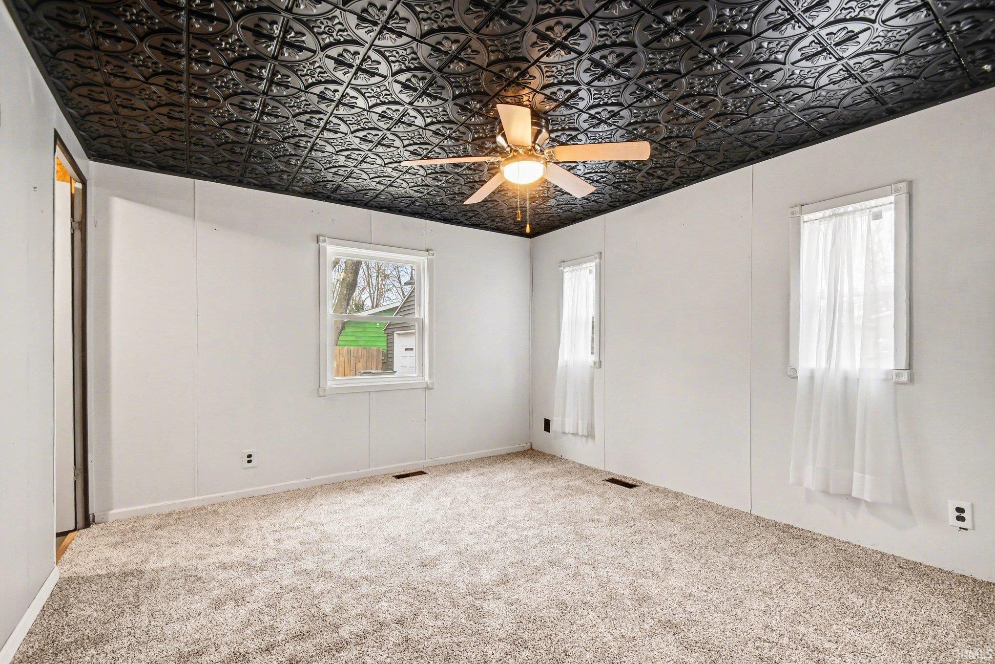 Carpeted empty room with an ornate ceiling and ceiling fan