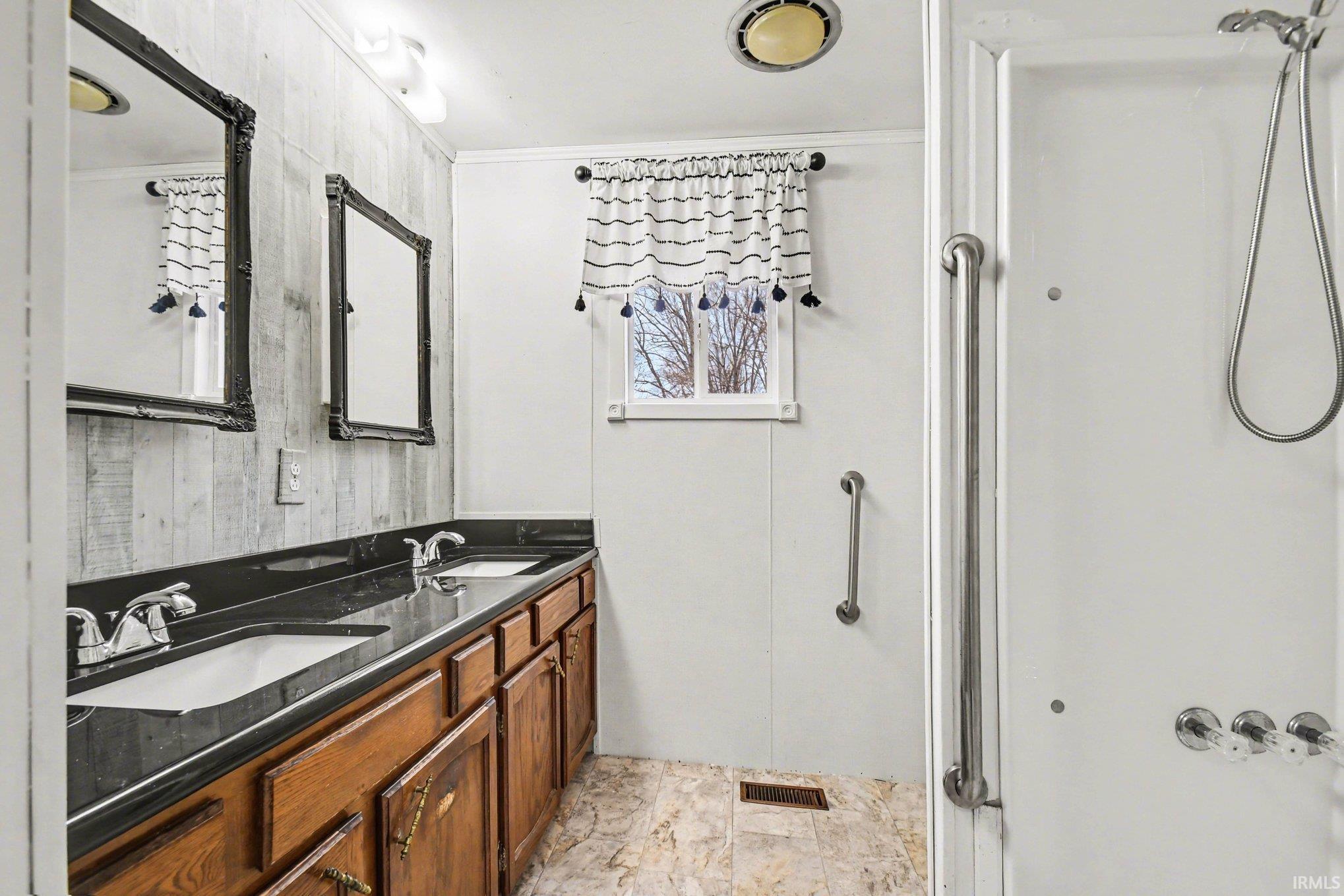 Full bathroom with double vanity, a shower stall, and crown molding