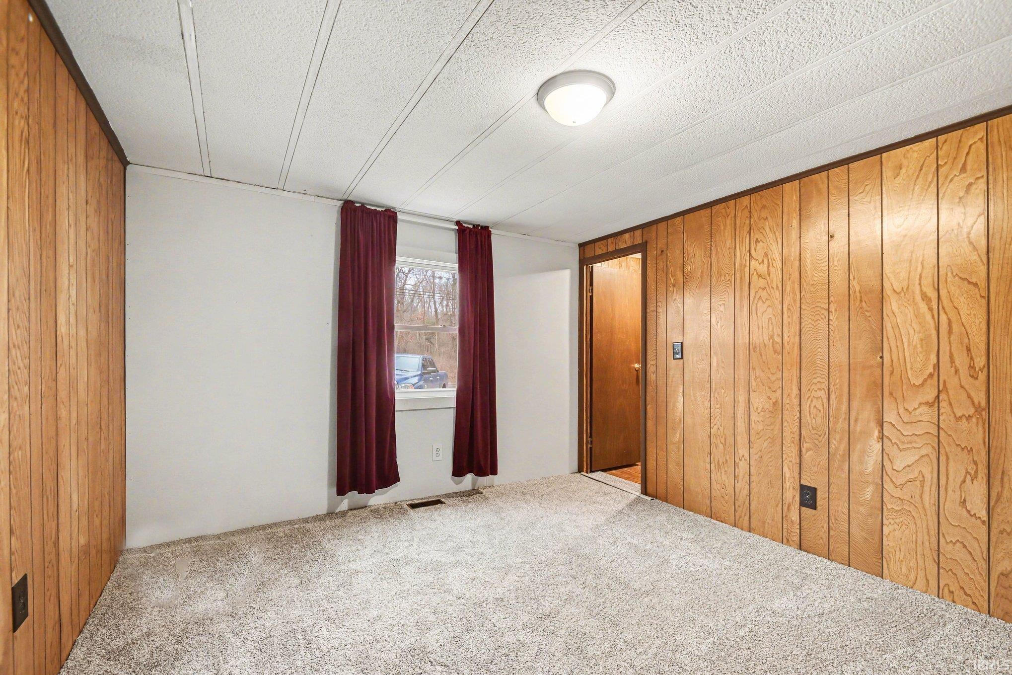 Carpeted spare room with wood walls and a textured ceiling