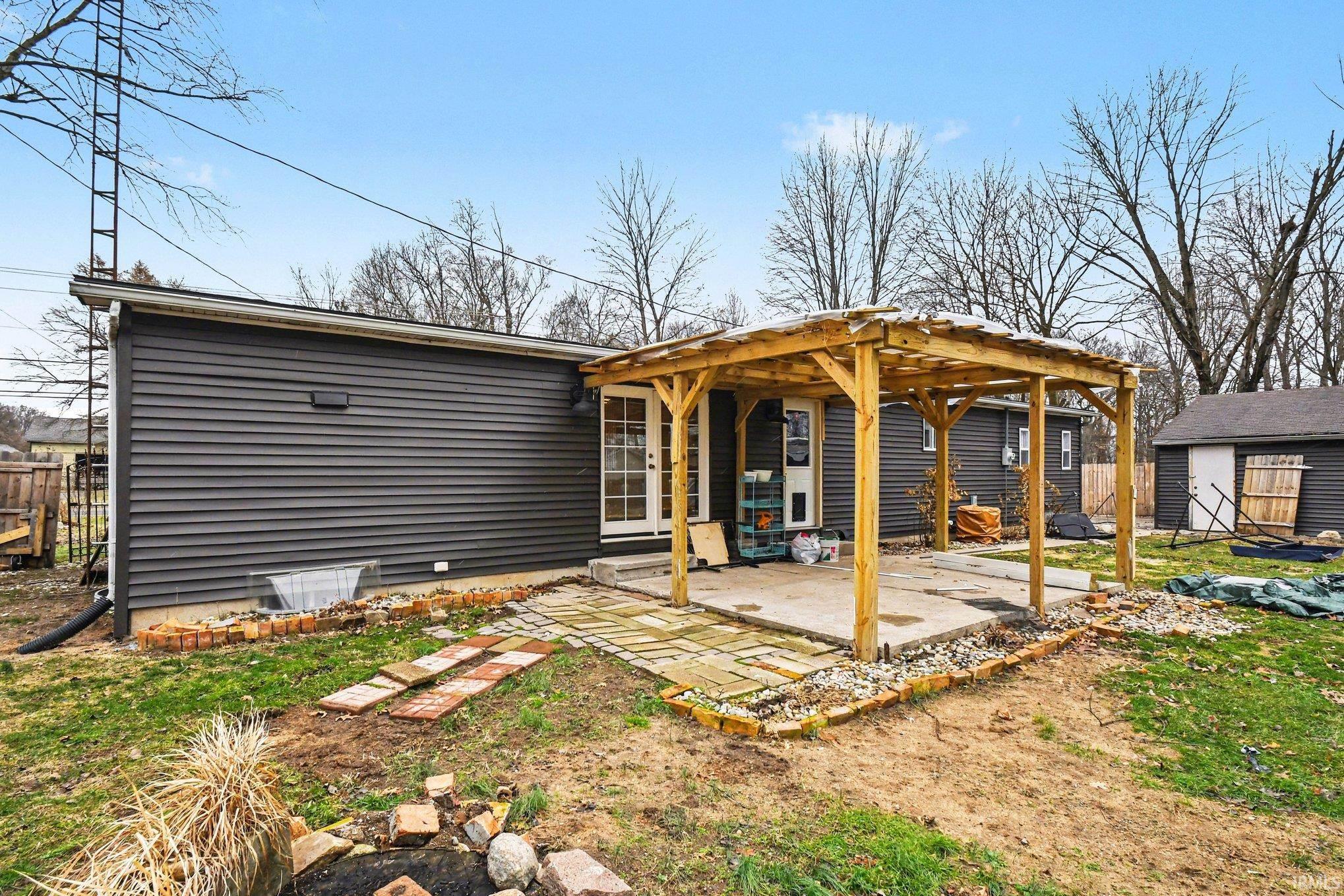 Rear view of property featuring an outbuilding, a pergola, and a patio area