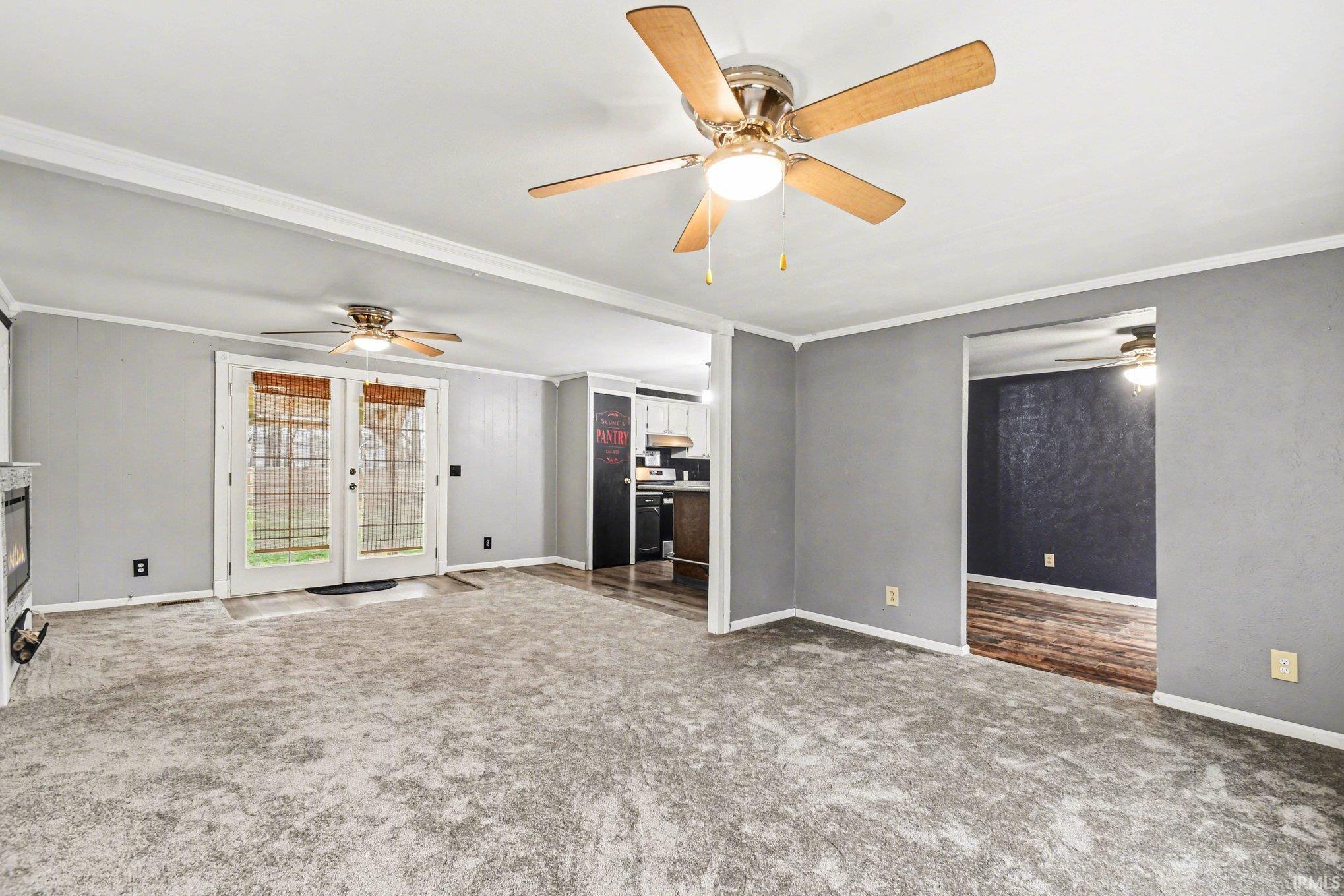 Unfurnished living room with crown molding, carpet flooring, and ceiling fan