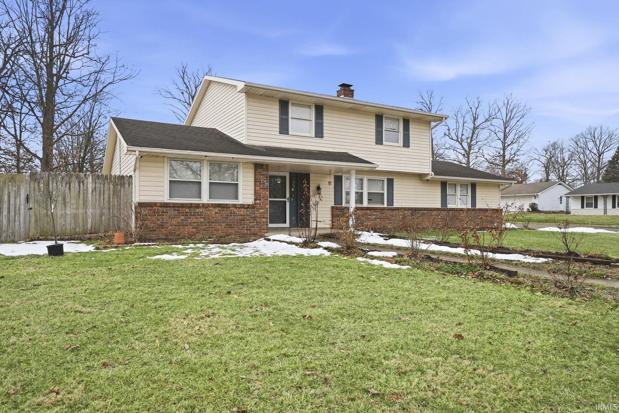 View of front of home featuring brick siding, a chimney, and a shingled roof