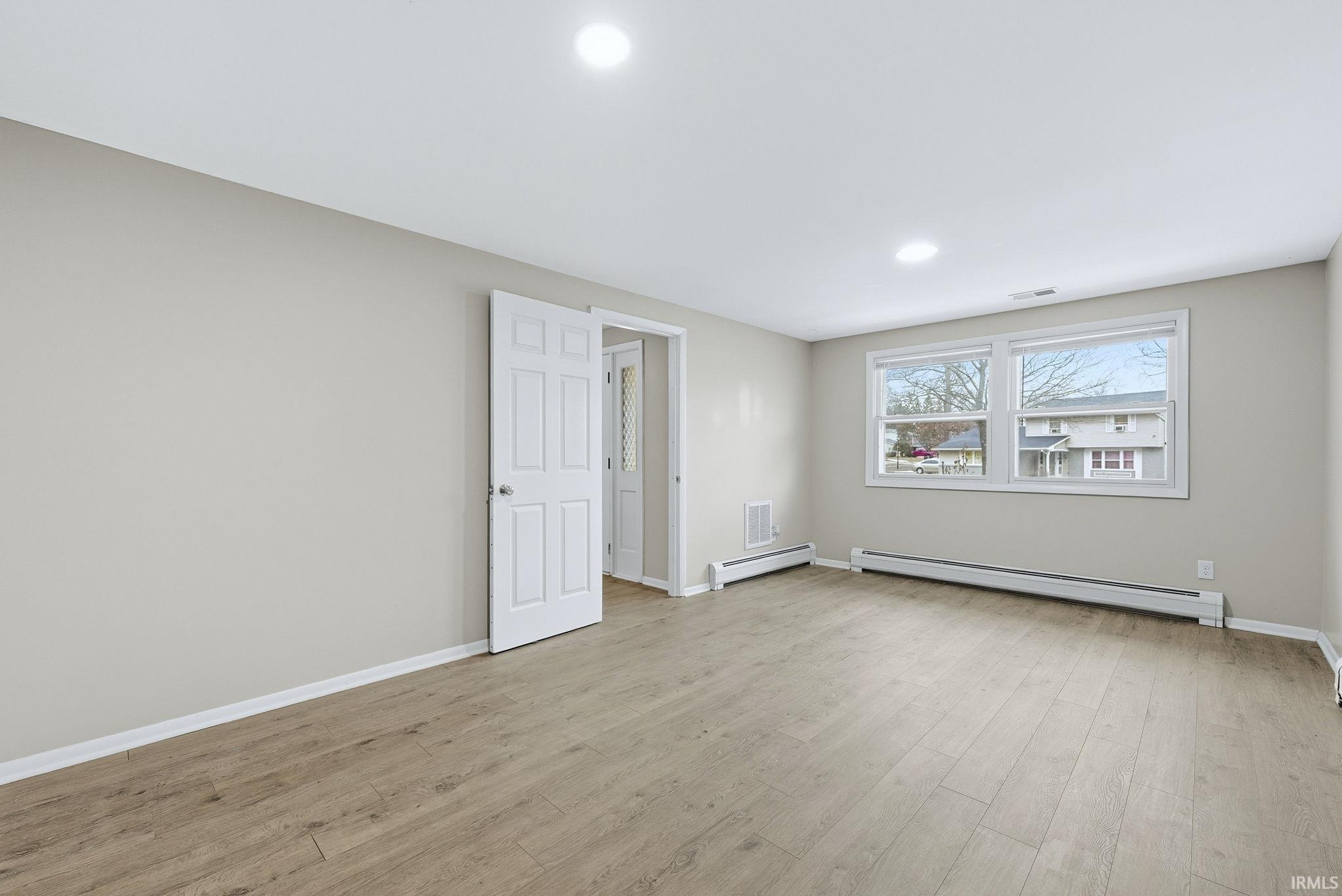 Unfurnished room with baseboard heating, light wood-type flooring, a baseboard radiator, and recessed lighting