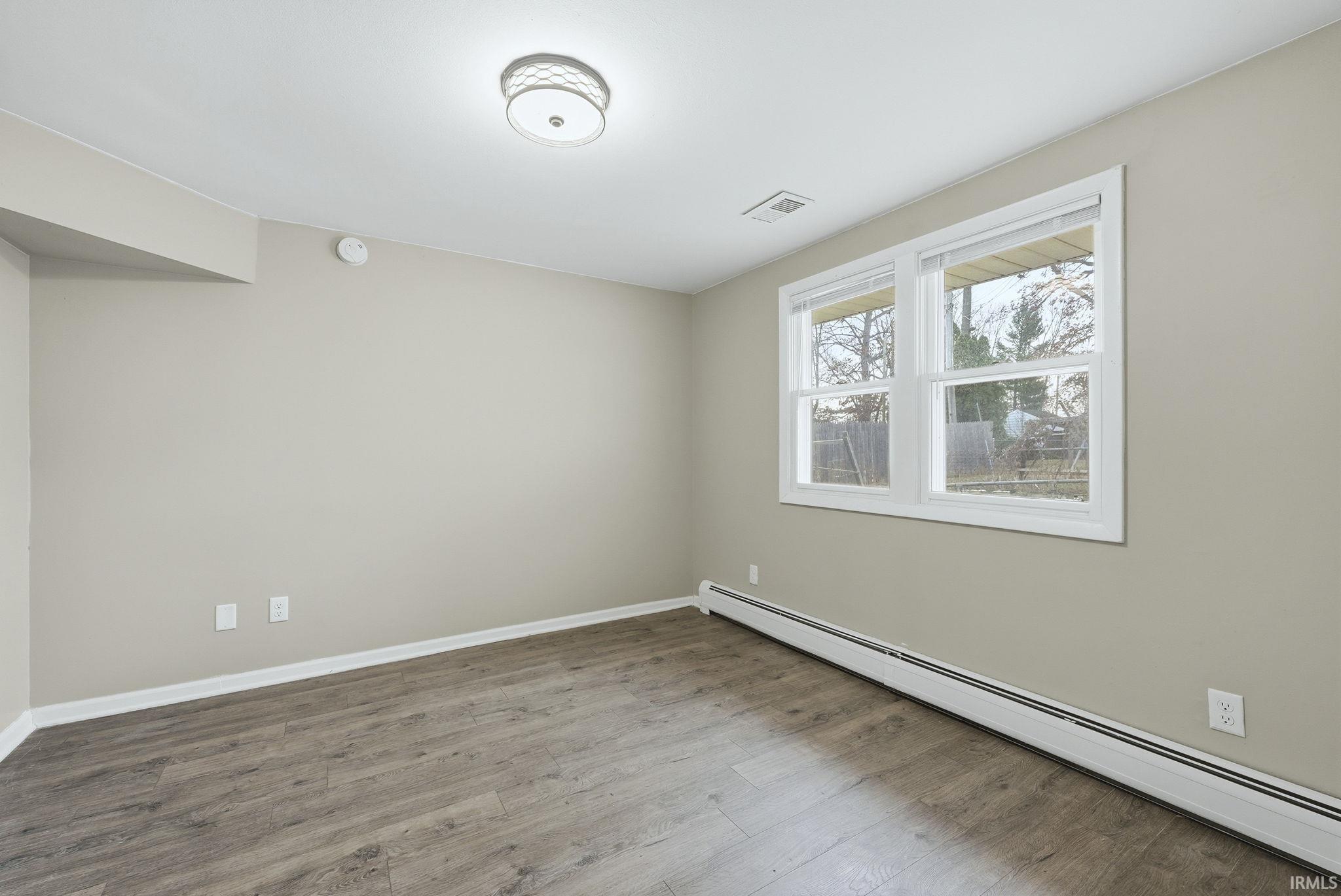 Empty room featuring a baseboard radiator and wood finished floors