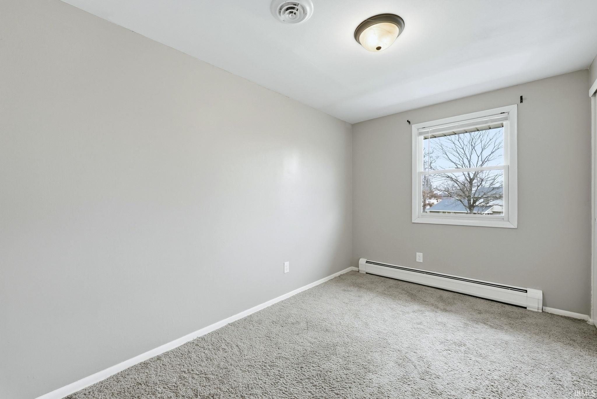 Spare room featuring a baseboard radiator and carpet