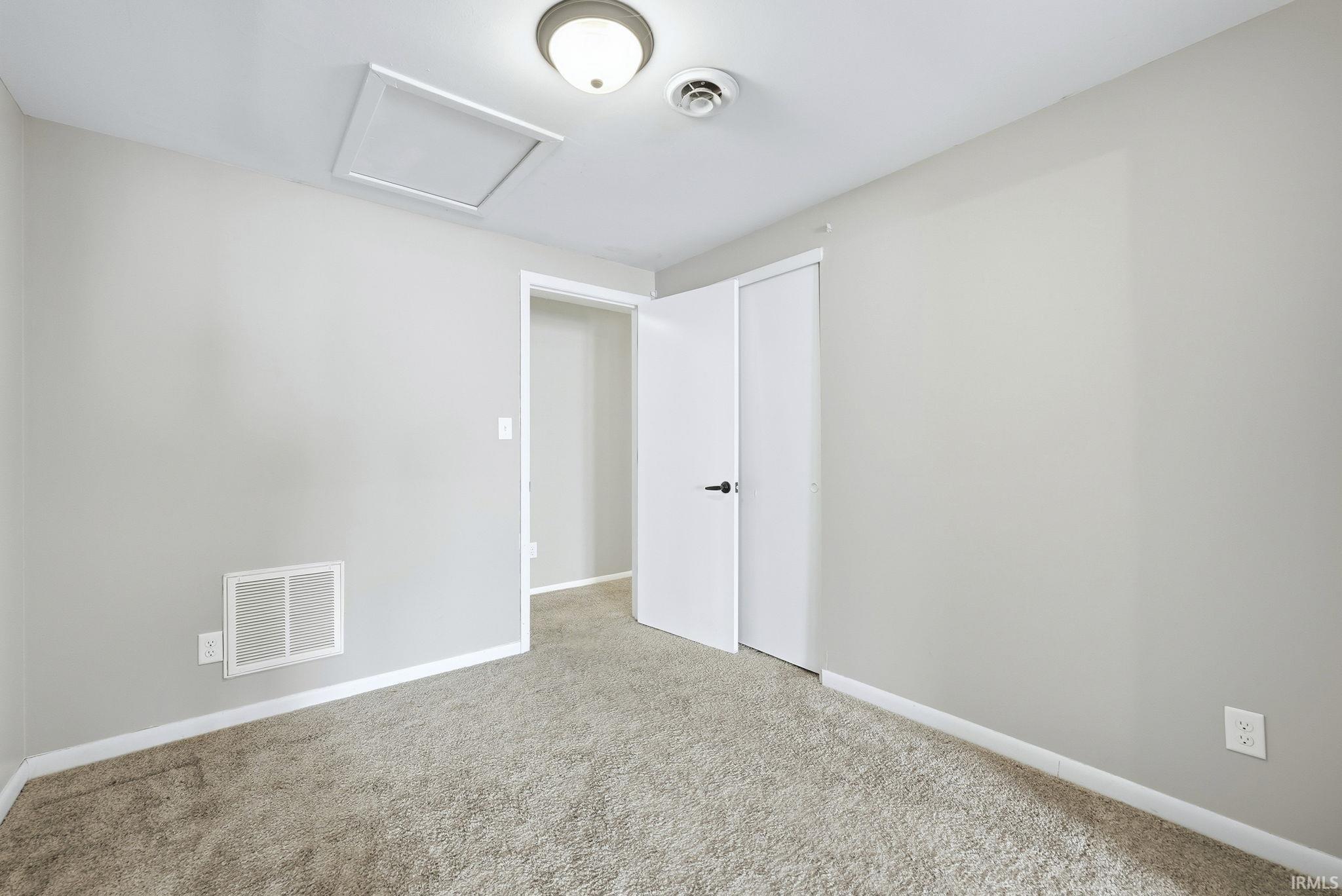 Spare room featuring attic access and carpet
