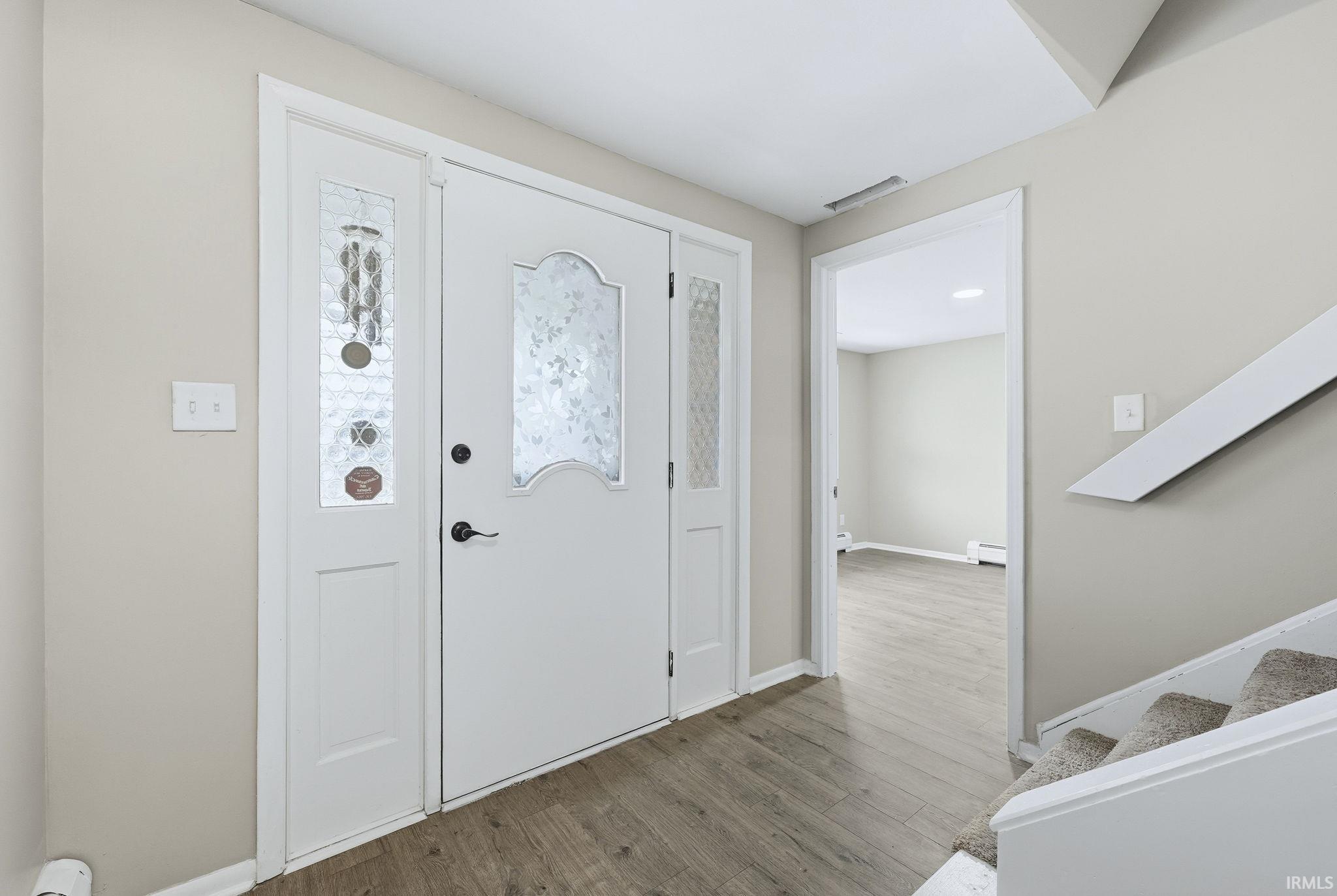 Entryway with wood finished floors and a baseboard heating unit