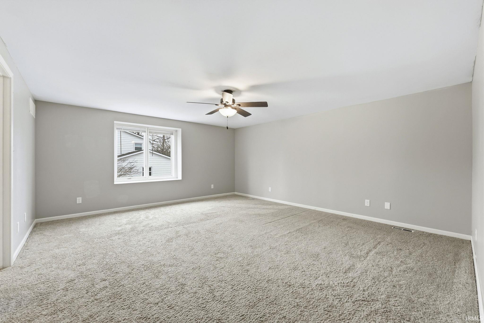 Spare room with light carpet and a ceiling fan