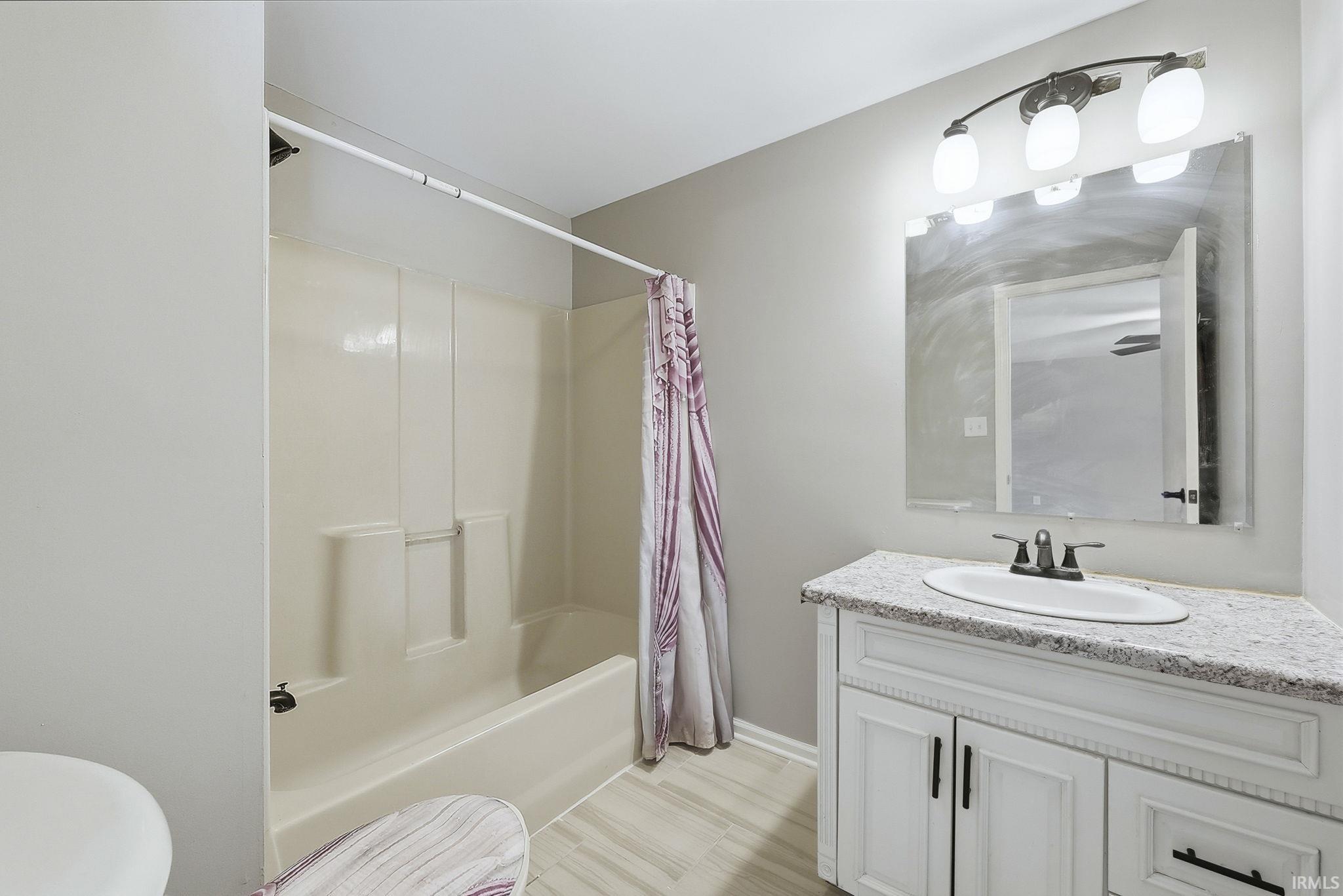 Bathroom featuring vanity and shower / bath combination with curtain