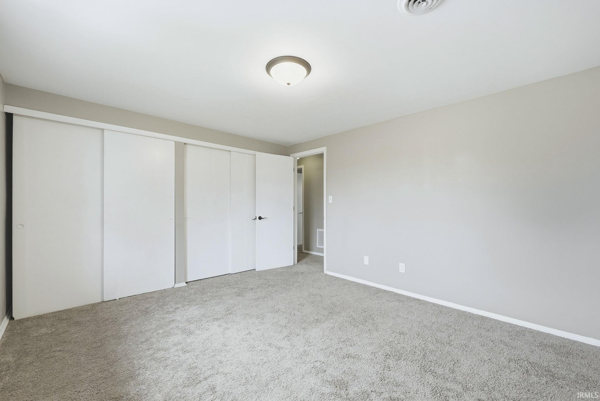 Unfurnished bedroom with light carpet and a closet