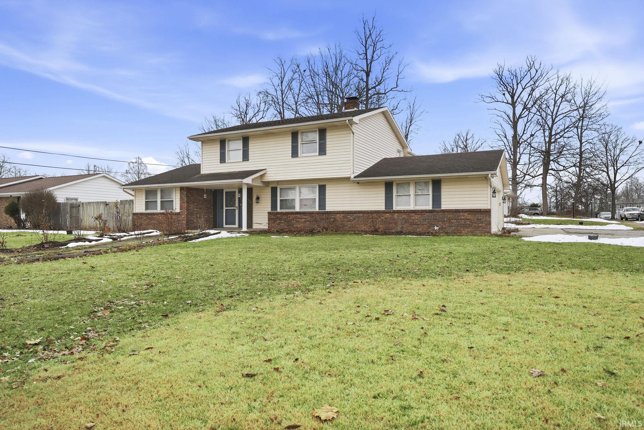 View of front of house featuring brick siding and a chimney