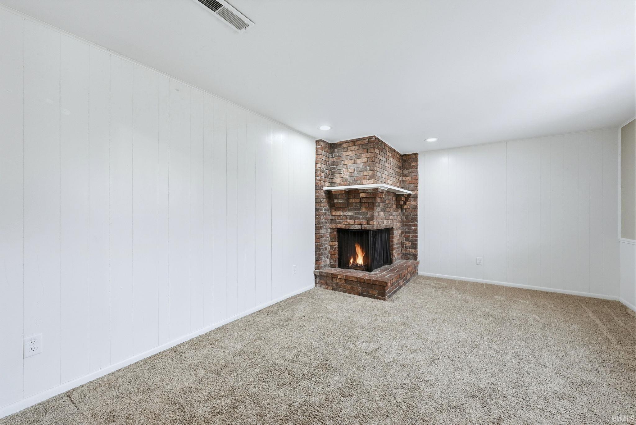 Unfurnished living room with a fireplace, carpet, and recessed lighting