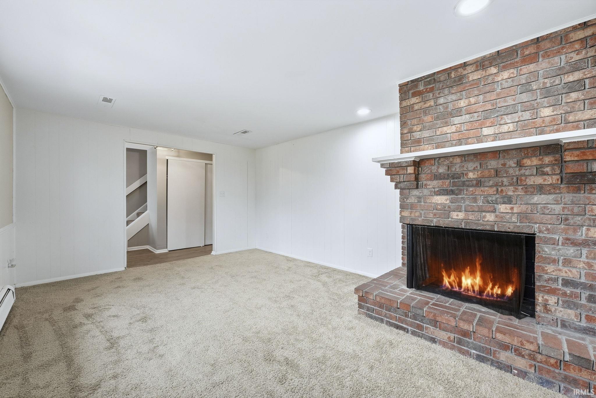 Unfurnished living room featuring light carpet, a brick fireplace, and recessed lighting