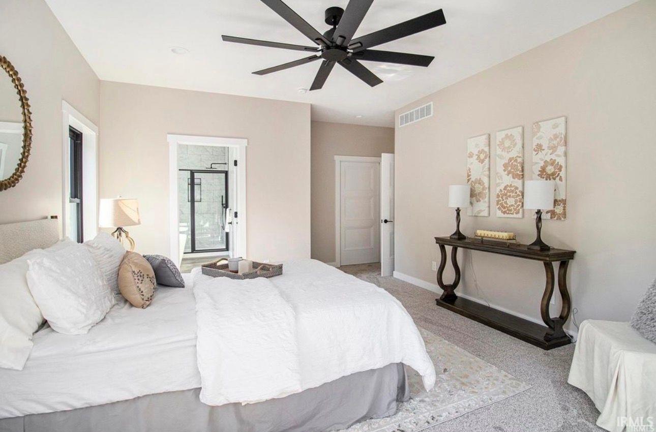 Bedroom with light colored carpet and a ceiling fan