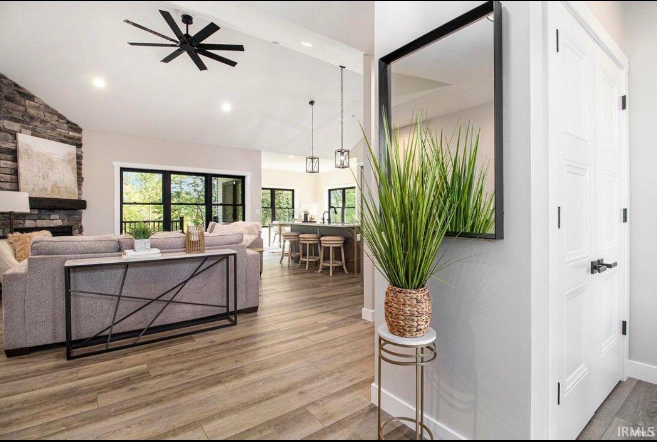 Living room featuring wood finished floors, lofted ceiling, a fireplace, and a ceiling fan
