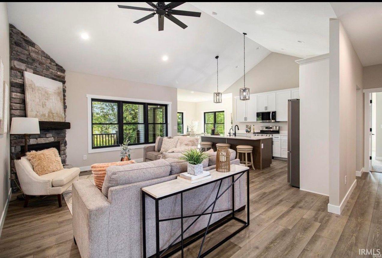 Living room featuring a high ceiling, a fireplace, a ceiling fan, and light wood finished floors