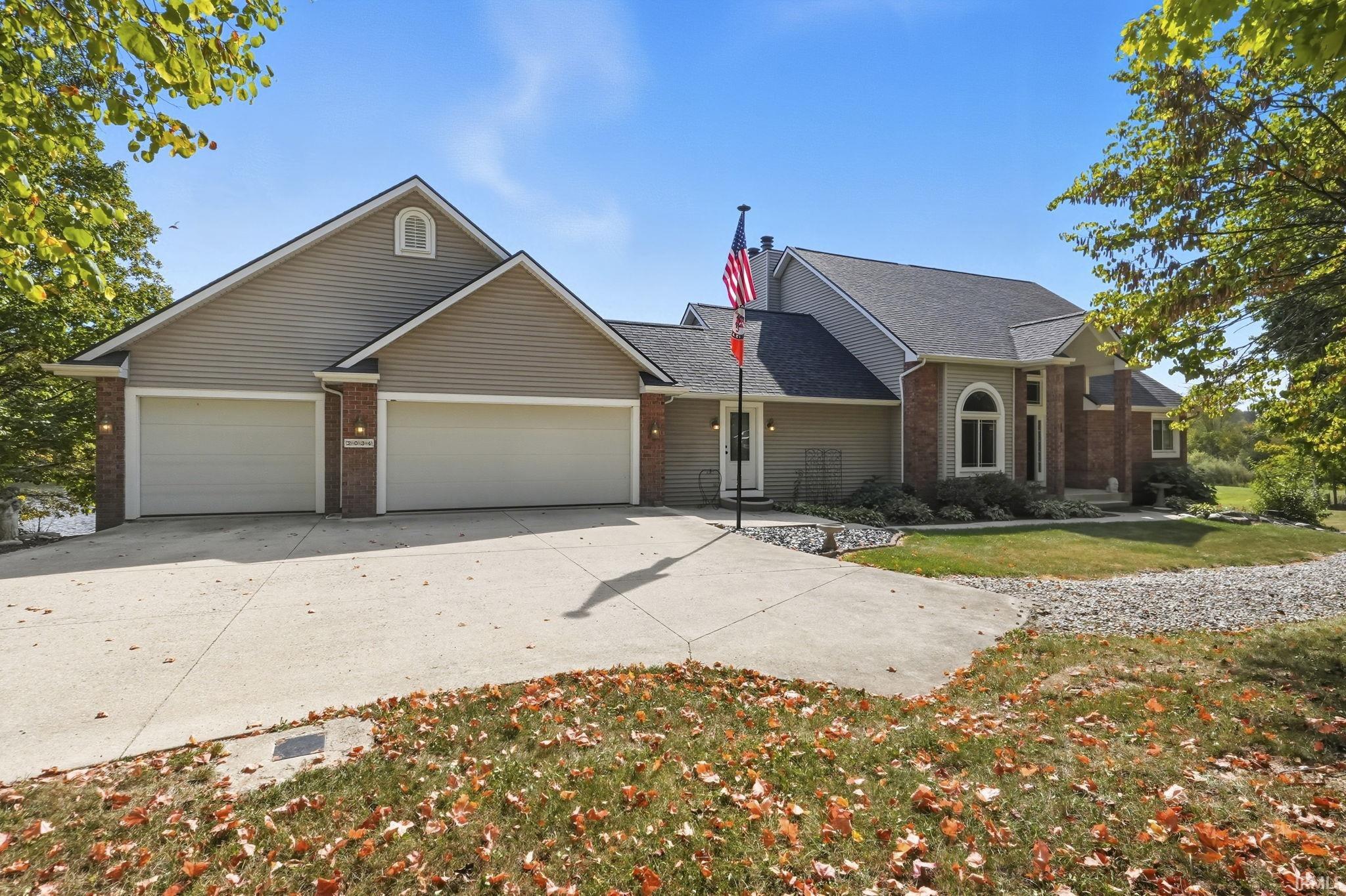 Traditional-style home with brick siding, driveway, a garage, and a front yard