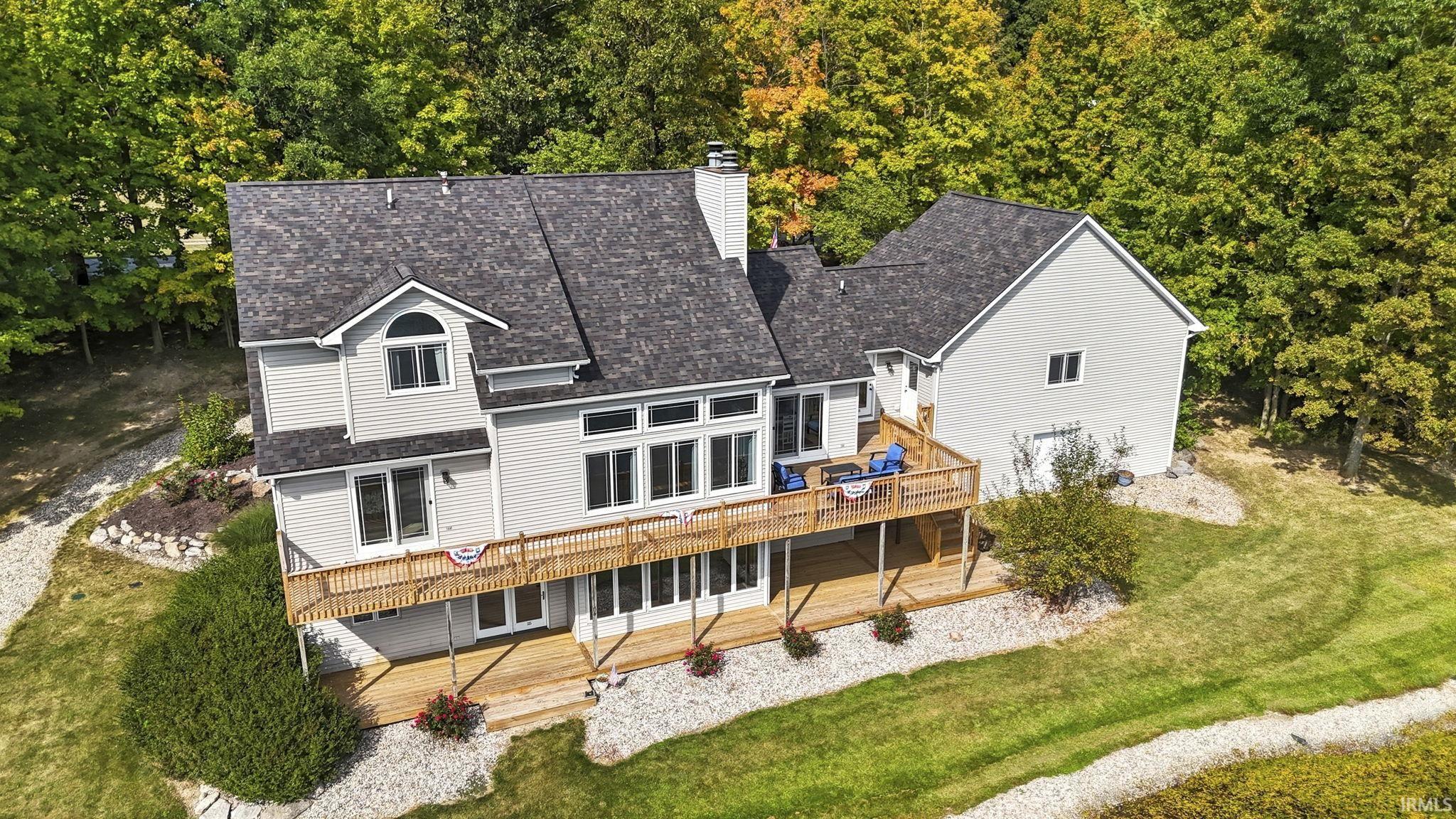 Back of property featuring a wooden deck, a shingled roof, a chimney, and a yard