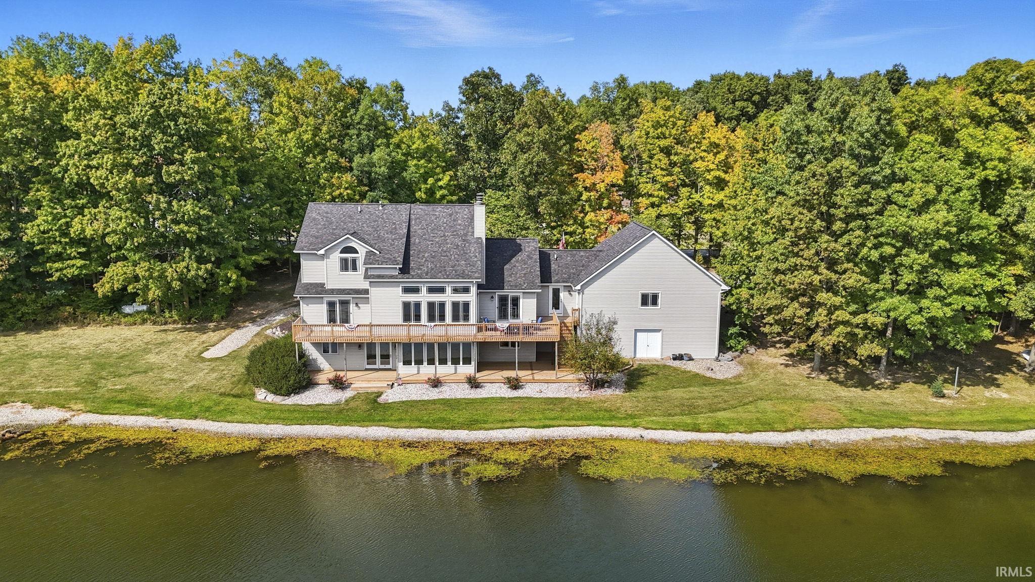 Back of property featuring a yard and a deck with water view