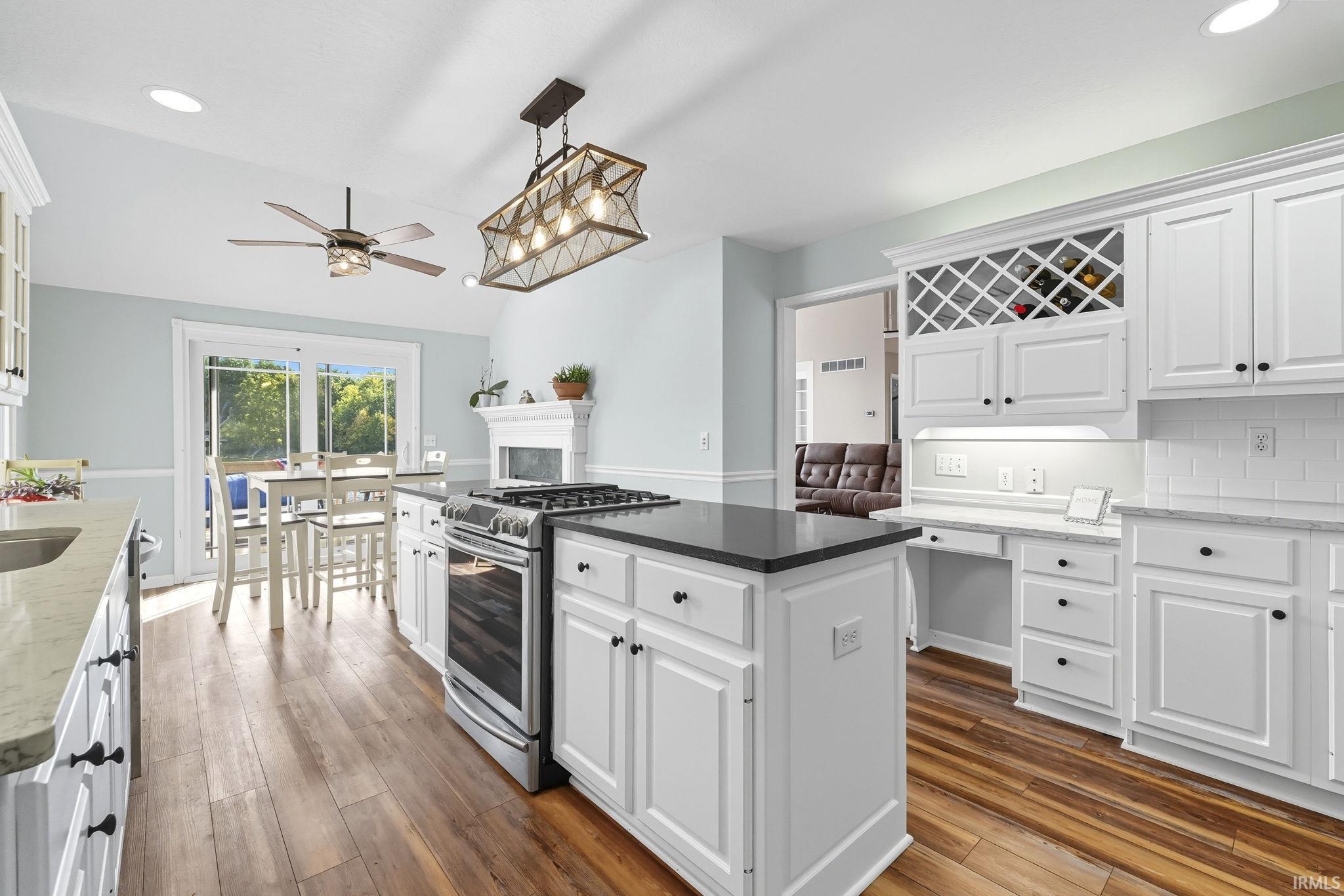 Kitchen featuring white cabinets, dark stone countertops, stainless steel range with gas cooktop, pendant lighting, and dark wood finished floors