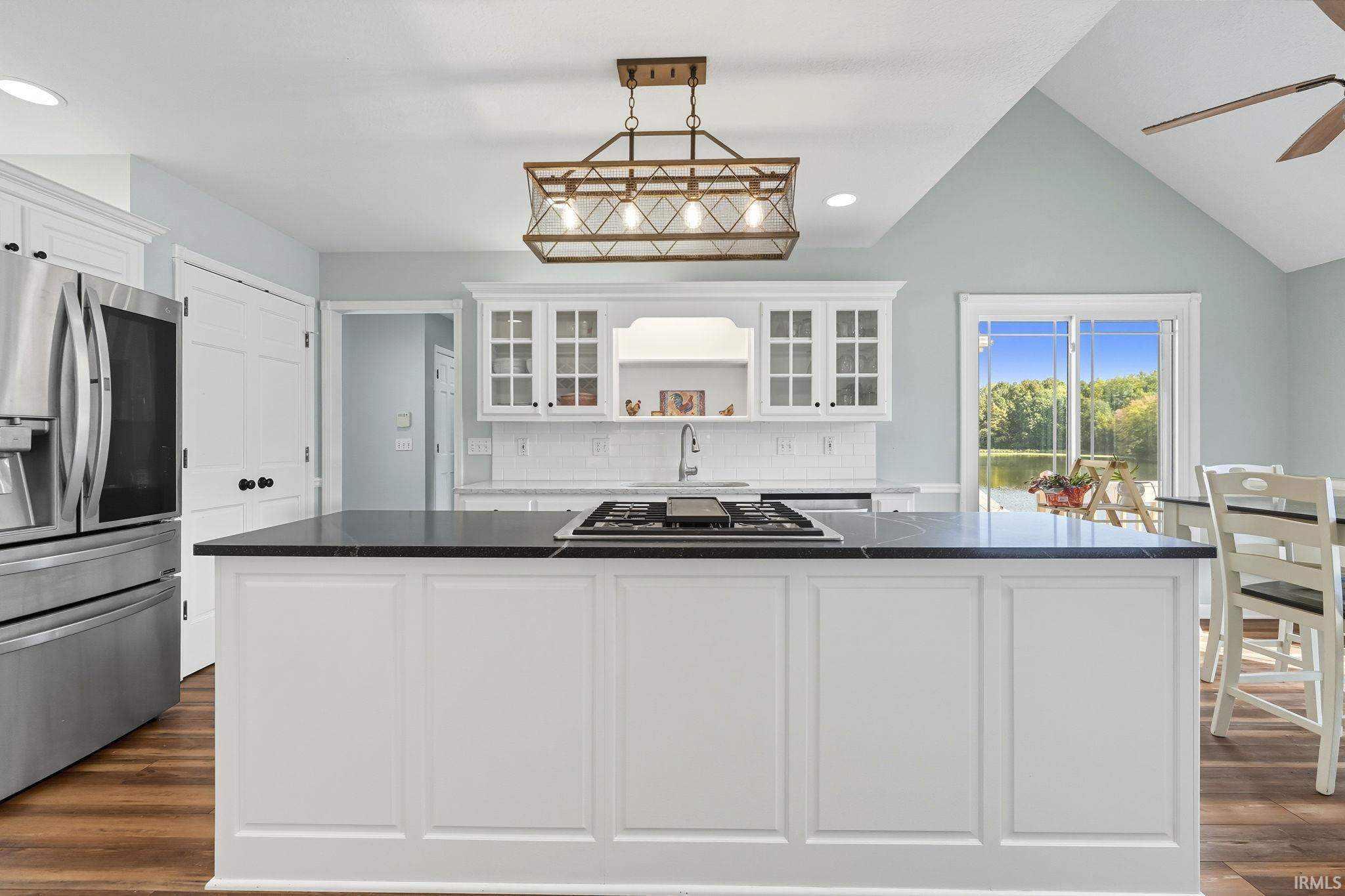 Kitchen featuring glass fronted cabinets, a kitchen island, stainless steel appliances, dark wood-style flooring, and white cabinets