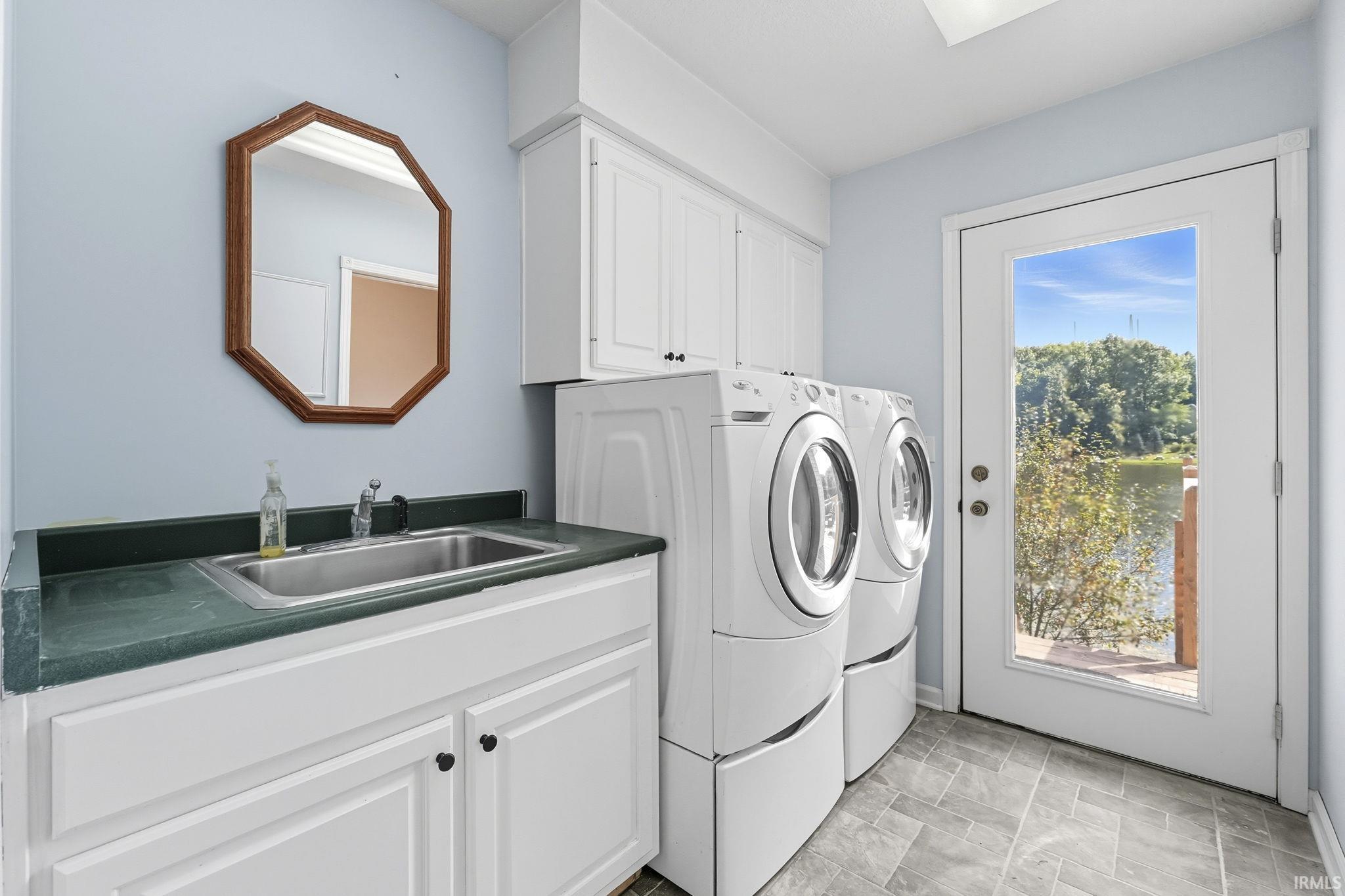 Laundry area featuring washer and dryer, cabinet space, and stone finish floors