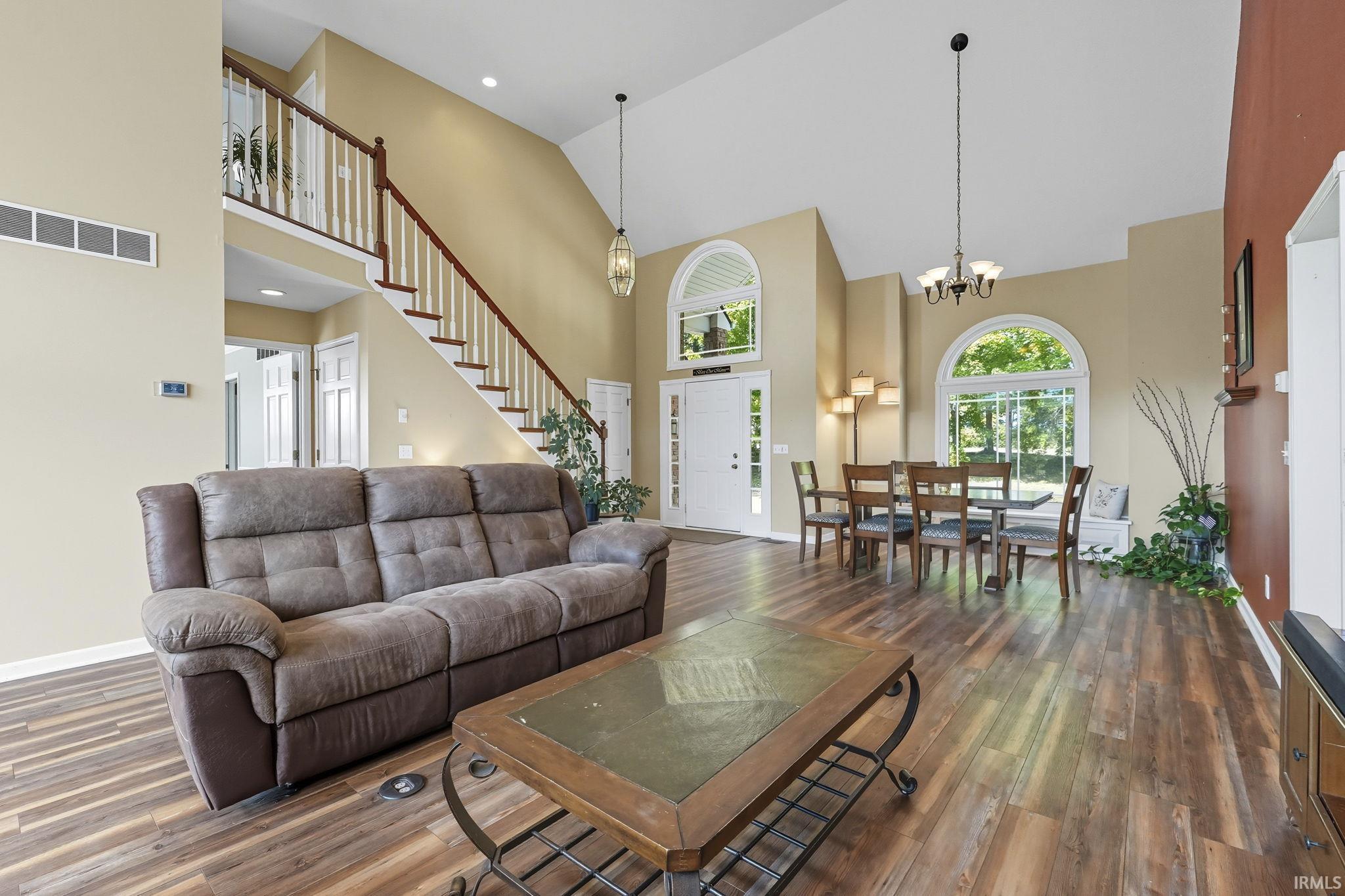 Living room featuring dark wood finished floors, suspended lighting, and lofted ceiling