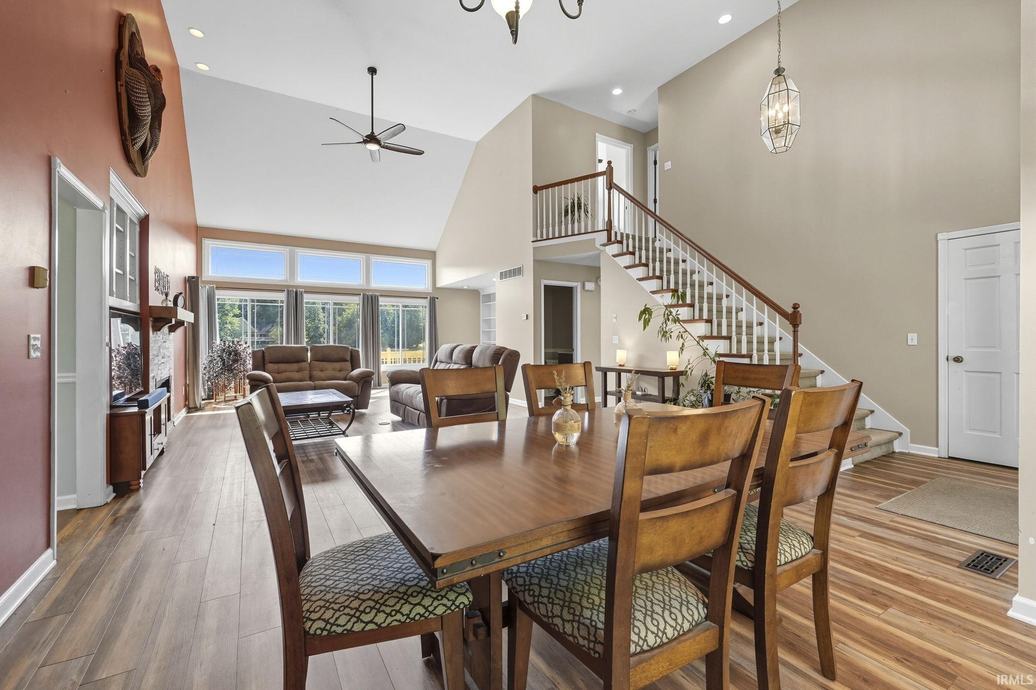Dining room with wood finished floors, ceiling fan, hanging lights, and lofted ceiling