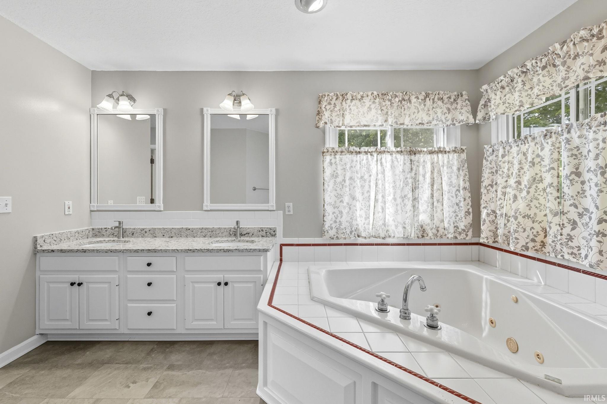 Full bath featuring double vanity and a jetted tub