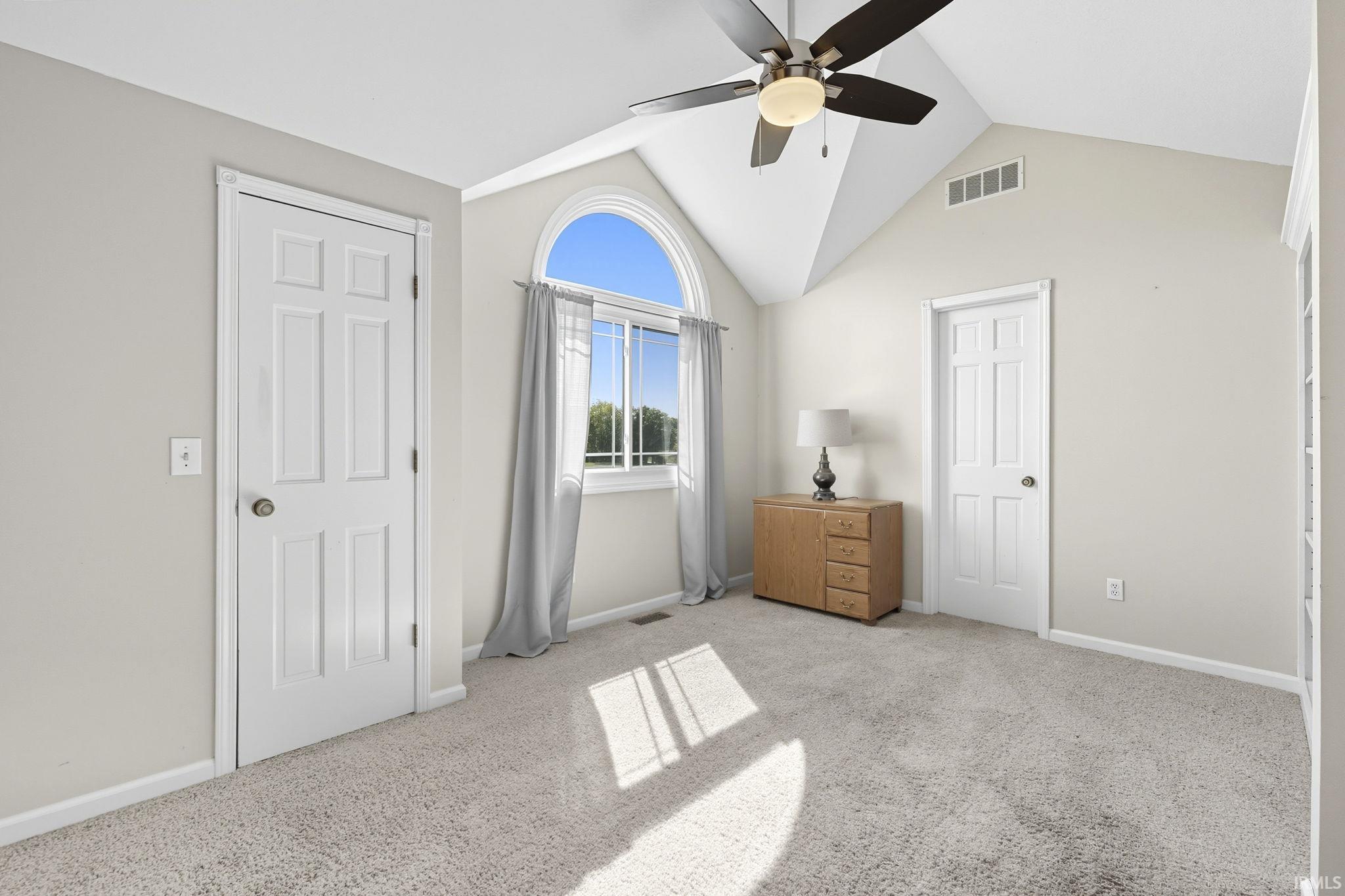 Unfurnished bedroom with light carpet, ceiling fan, and a high ceiling