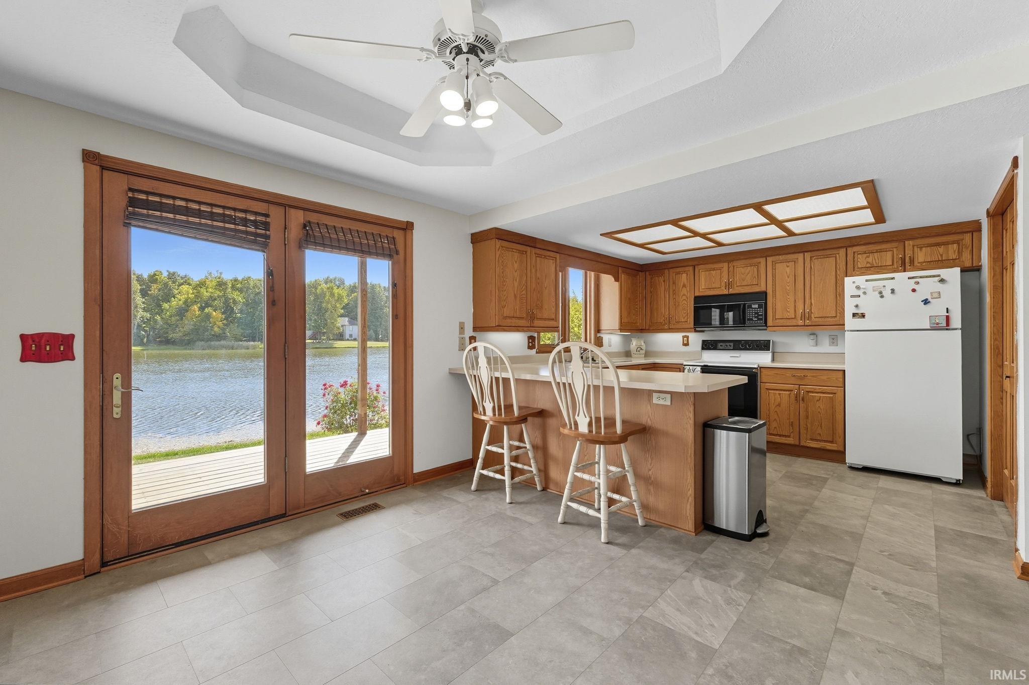 Kitchen with light countertops, a peninsula, freestanding refrigerator, a breakfast bar, and wood finish cabinetry